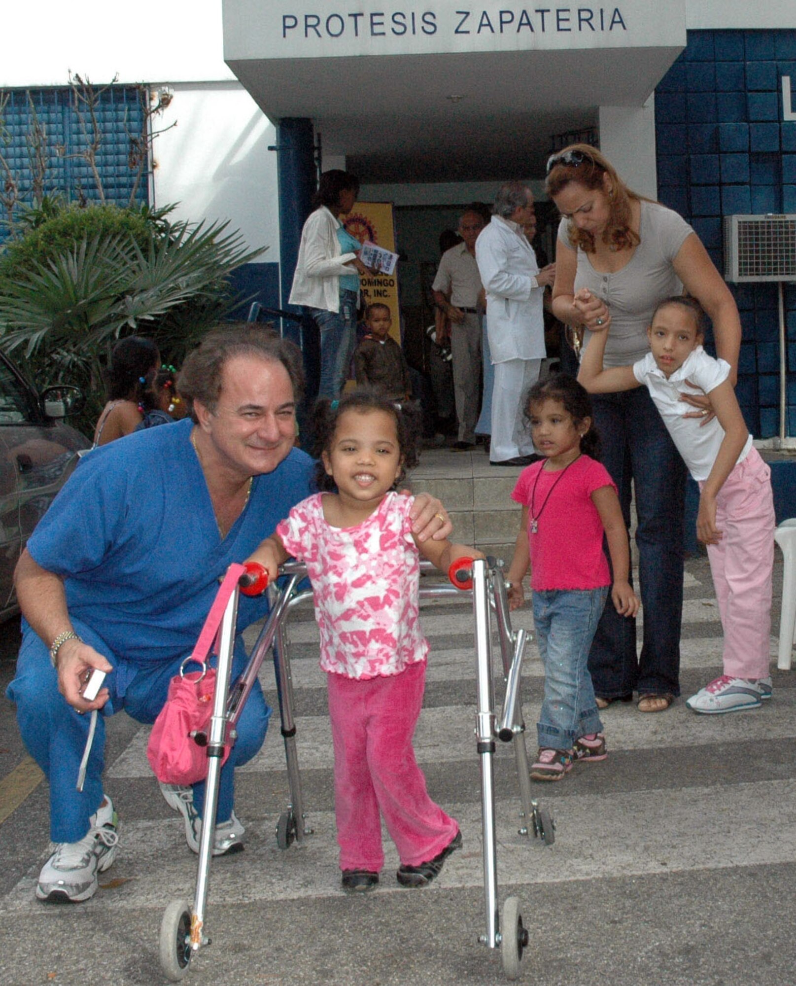 SANTO DOMINGO, DOMINICAN REPUBLIC — Dr. Paul Wright, a Notre Dame alumni a retired physician kneels with a patient at an orthopedic clinic here.  New and gently used clothing was distributed to the children at the clinic.