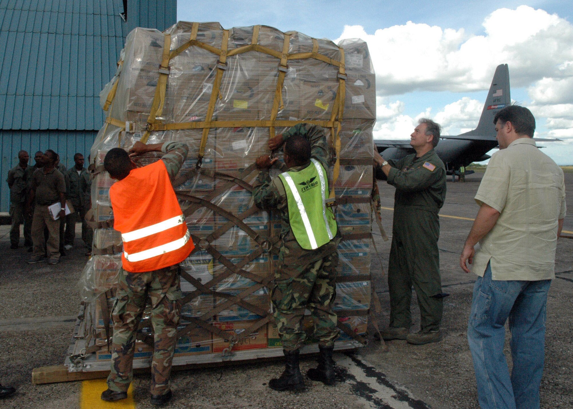 SANTO DOMINGO, DOMINICAN REPUBLIC — Air Force Reserve Master Sgt. Mick Burgett, a loadmaster with the 910 Airlift Wing, works with local Dominican army soldiers to break down a pallet of donated clothing for distribution.  