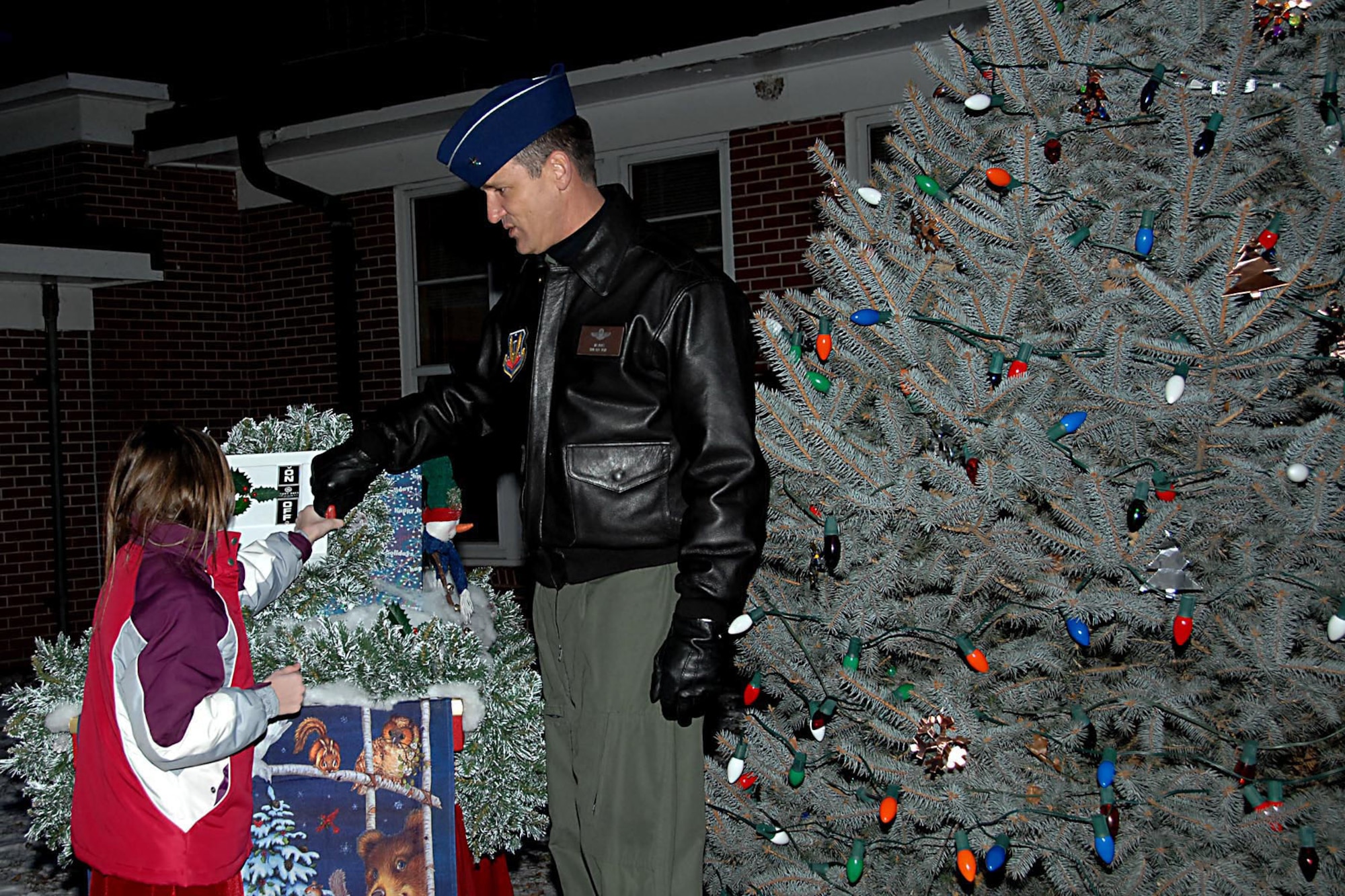 Offutt Air Force Base, Neb. --- Brig. Gen. James J. Jones, 55th Wing commander, and Isabel VanHuffel, daughter of Lt. Col. John VanHuffel, Air Combat Command, Operations, flip the switch light up Offutt's Holiday Tree at the Tree Lighting Ceremony Dec. 4 at the Strategic Air Command Memorial Chapel. Offutt's Holiday Tree is an 8 foot live tree that will continue to grow over the years. (U.S. Air Force Photo By Kendra Williams)