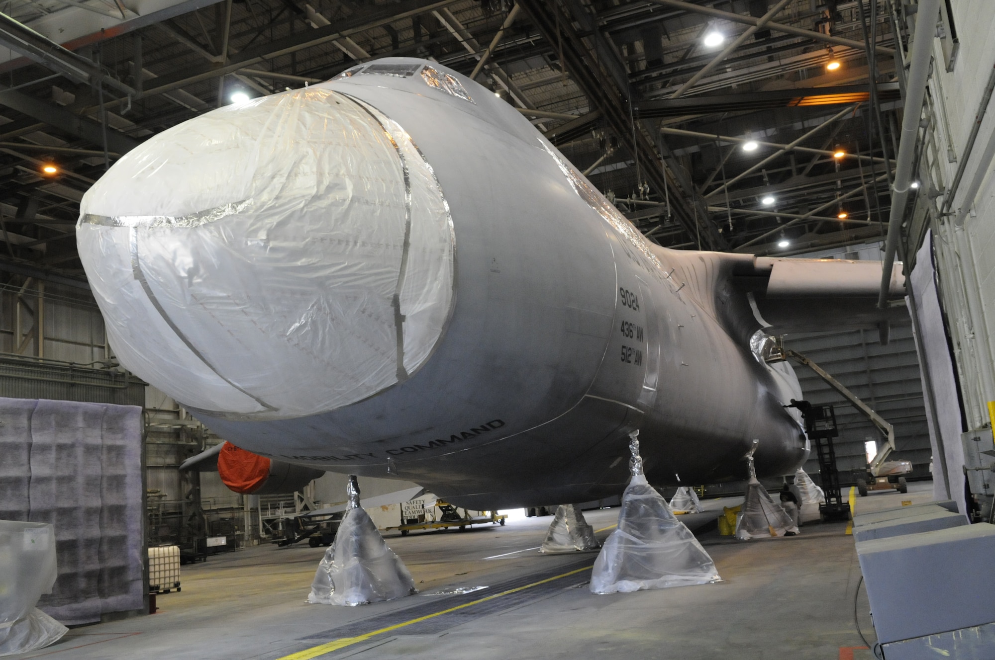 The C-5M sits in a depaint hangar where workers have masked the seams, composite areas and antennas in order to spray on stripper to depaint the aircraft. U. S. Air Force photo by Sue Sapp
