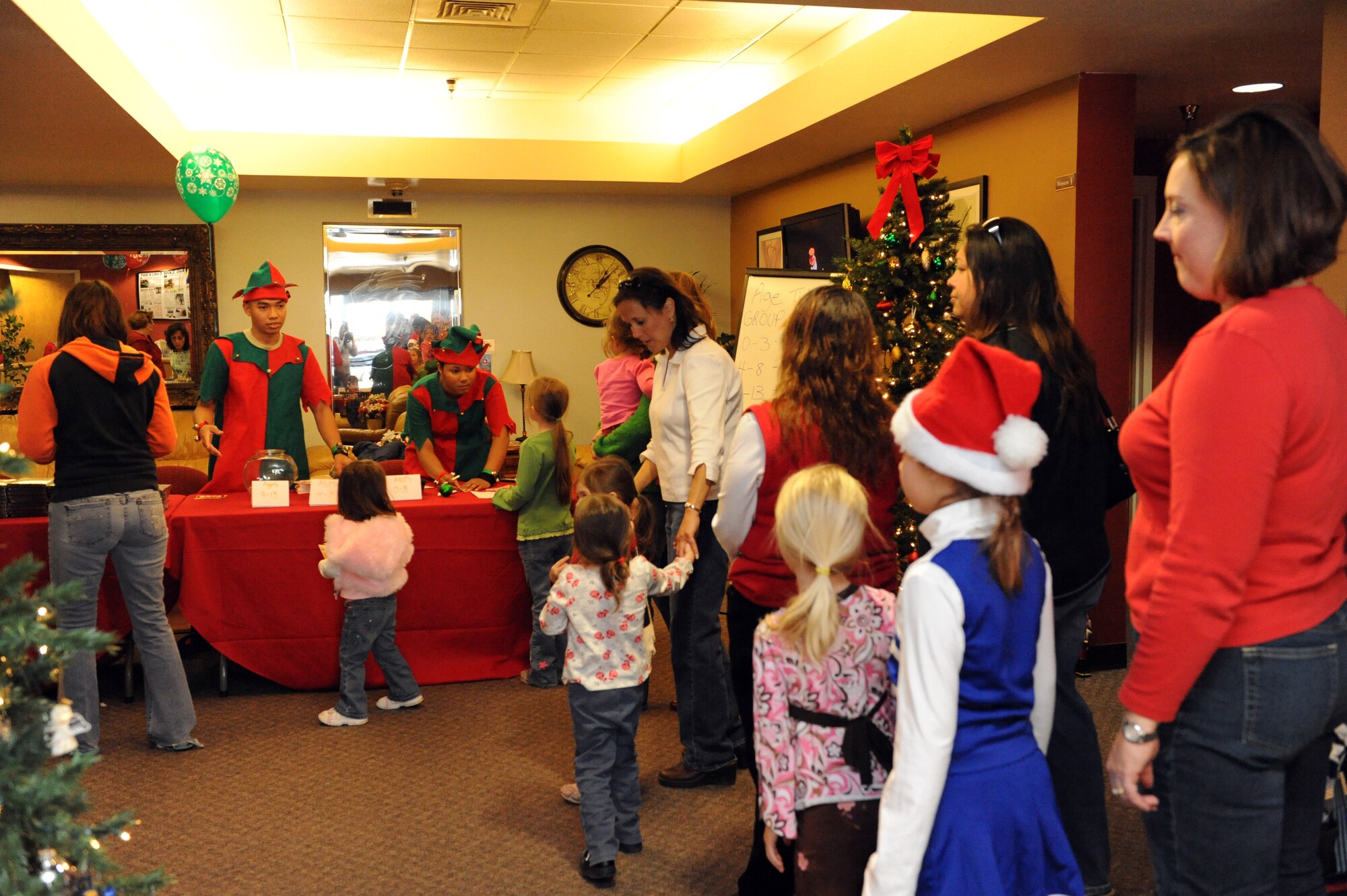 Two Airmen from the 49th Logistics Readiness Squadron work at the "Elves table" handing out passports during the International Children's Festival at the Community Center at Holloman Air Force Base, N.M., Dec. 13. The "Elves table" is the children's first stop upon their arrival to the festival. They then check out all the stations displaying the holiday traditions of many different countries where they get their passport stamped. (U.S. Air Force photo/Airman 1st Class Sondra Escutia)