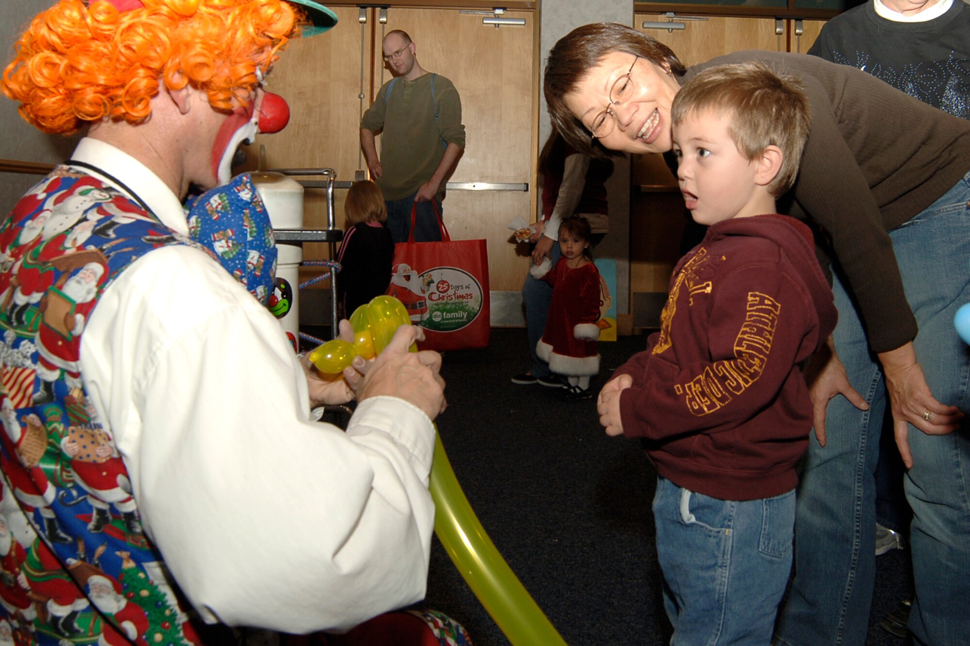 MCCONNELL AIR FORCE BASE, Kan. -- Austin Atkins and his grandmother Susan Atkins wait for Troubles the clown to finish making a balloon animal, Dec. 13. During Santa’s visit to the Dole Center, participants made gingerbread ornaments, holiday coloring pages, Christmas chains and candy cane mouse ornaments. (Photo by Airman 1st Class Maria Ruiz)