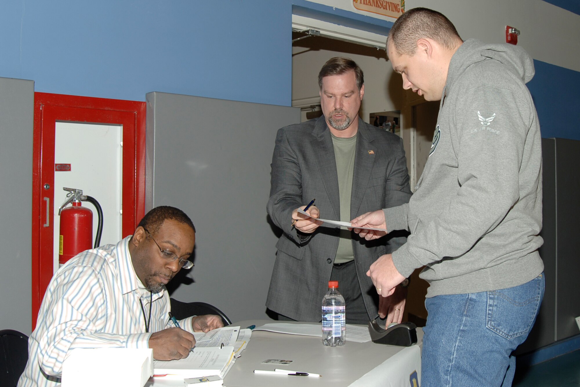 MCCONNELL AIR FORCE BASE, Kan. -- Staff Sgt. Buck Frank, 22nd Operations Support Squadron, receives information on his new Southwind Housing cross-over bridge access card from Kara Williams and Steve Eftink, 22nd Security Forces squadron members, during the quarterly town hall meeting held at the Youth Center Dec. 10. Topics addressed at the meeting were housing repair projects, the new pedestrian bridge card system, updates on housing privatization and golf course revitalization projects. At the end of the meeting, the Army and Air Force Exchange Service also raffled away a free MP3 player. (Photo by Airman 1st Class Maria Ruiz)