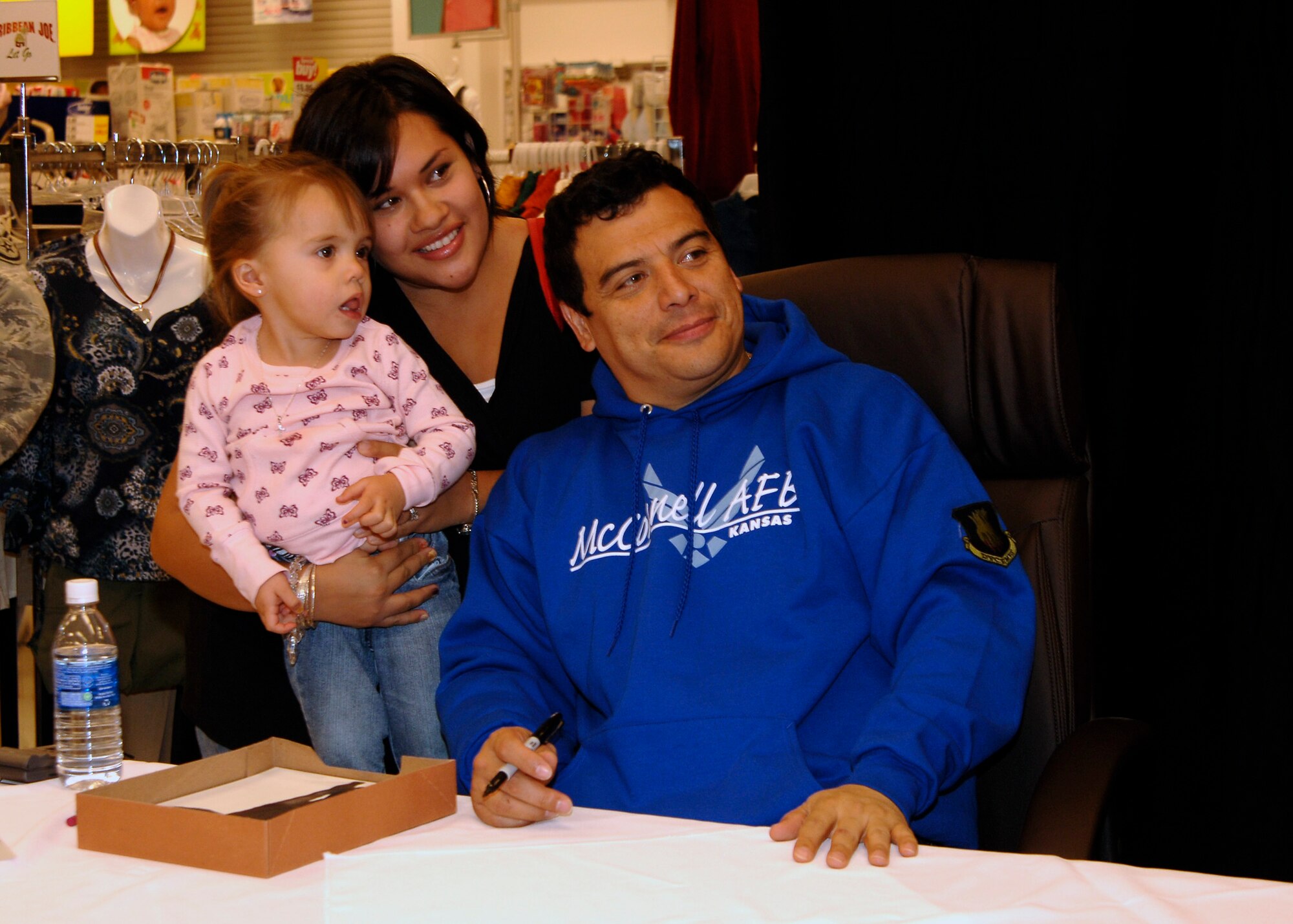MCCONNELL AIR FORCE BASE, Kan. – Lorraine Ditch and her daughter, Raylene, 2, meet comedian Carlos Mencia, Dec. 12, at the McConnell Base Exchange. Mr. Mencia took time to meet Airman, take group photos and sign autographs before performing stand-up comedy at the Cotillion in Wichita. (Photo by Senior Airman Anthony Mejia)
