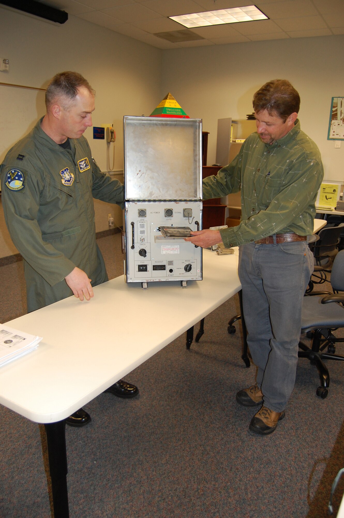 Dave Decker, 341st Operations Support Squadron senior codes instructor, demonstrates how a recording can communicate with an ICBM in the field to transmit information, passwords and lock the weapon until a presidential order is issued, as Capt. Darrel DeLeon, 341st OSS chief of ICBM wing codes operations, looks on. (U.S. Air Force photo/Senior Airman Emerald Ralston)