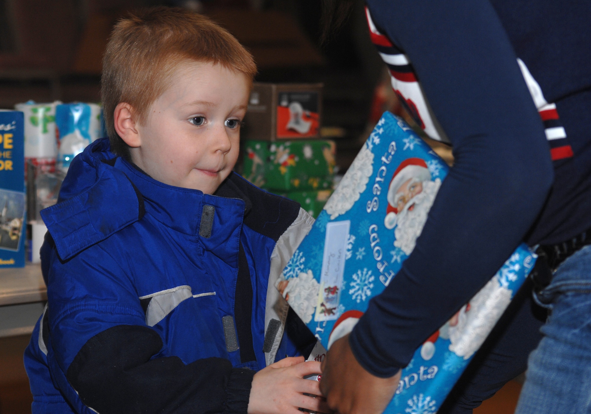 Cuilen Oglesbee, son of Maj. Eric and Davida Oglesbee, reaches for gifts for his mom and dad during the Aviano Officers and Civilians Spouses Club annual Christmas Cottage Dec. 16 at the Community Center. The cottage, hosted by the AOCSC, allows children to pick out a gift, wrap it and give it to their parents for Christmas. (U.S. Air Force photo/Senior Airman Justin Weaver)