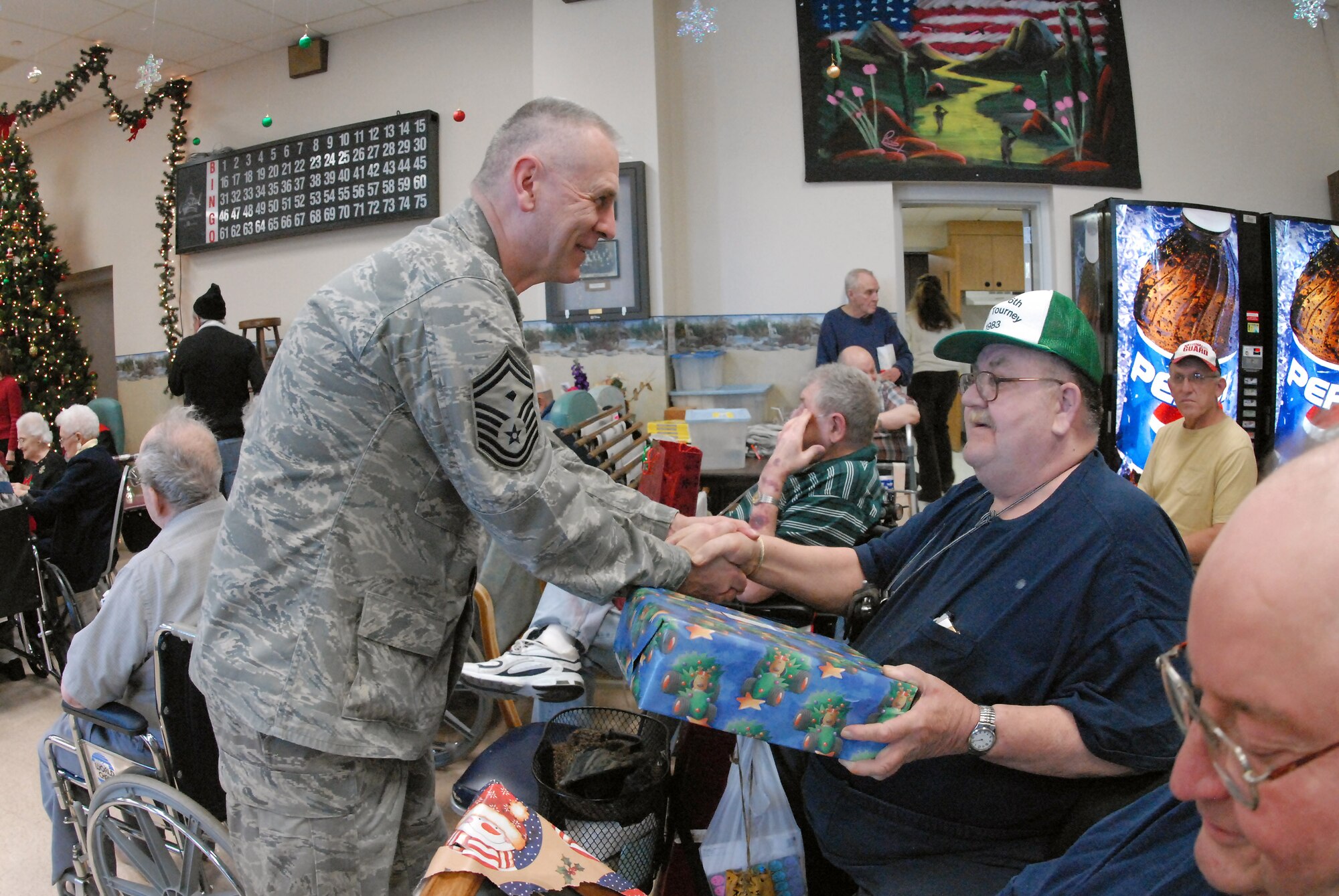Senior Master Sgt. Paul Tangen gives a Christmas gift to Army Vietnam War veteran Roger Severson at the North Dakota Veteran's Nursing Home Dec. 10 in Lisbon, N.D. The gifts are given to veterans at the nursing home by the North Dakota Air and Army National Guard each December using funds raised through personal donations given by the North Dakota National Guard members. Sergeant Tangen is the the 119th Wing first sergeant. (U.S. Air Force photo/Senior Master Sgt. David H. Lipp) 