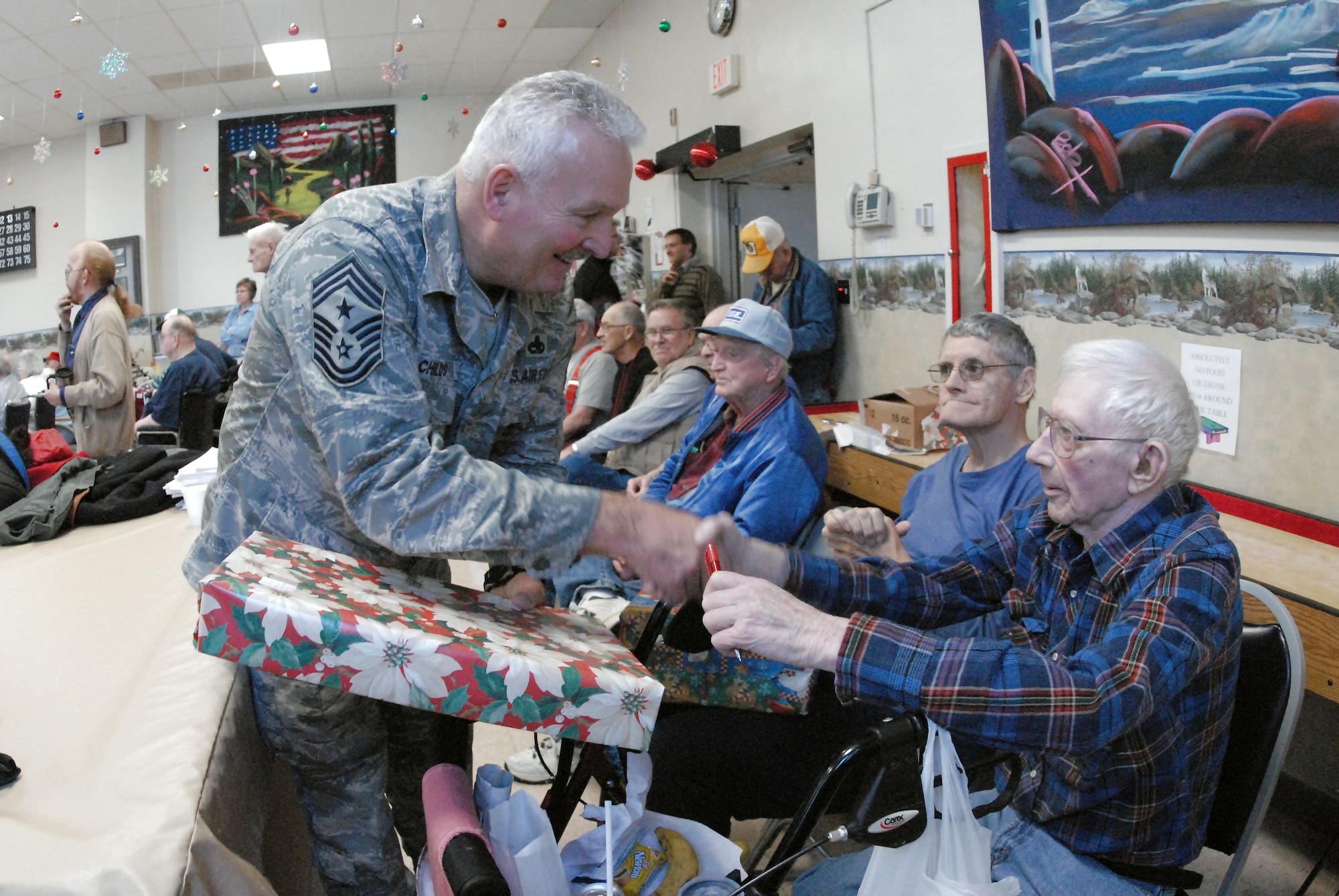 Chief Master Sgt. Brad Childs gives a Christmas gift to Army Korean War veteran Ervin Barfuss at the North Dakota Veteran's Nursing Home Dec. 10 in Lisbon, N.D. The gifts are given to veterans at the nursing home by the North Dakota Air and Army National Guard each December using funds raised through personal donations given by the North Dakota National Guard members. Chief Childs is the the 119th Wing command chief. (U.S. Air Force photo/Senior Master Sgt. David H. Lipp) 