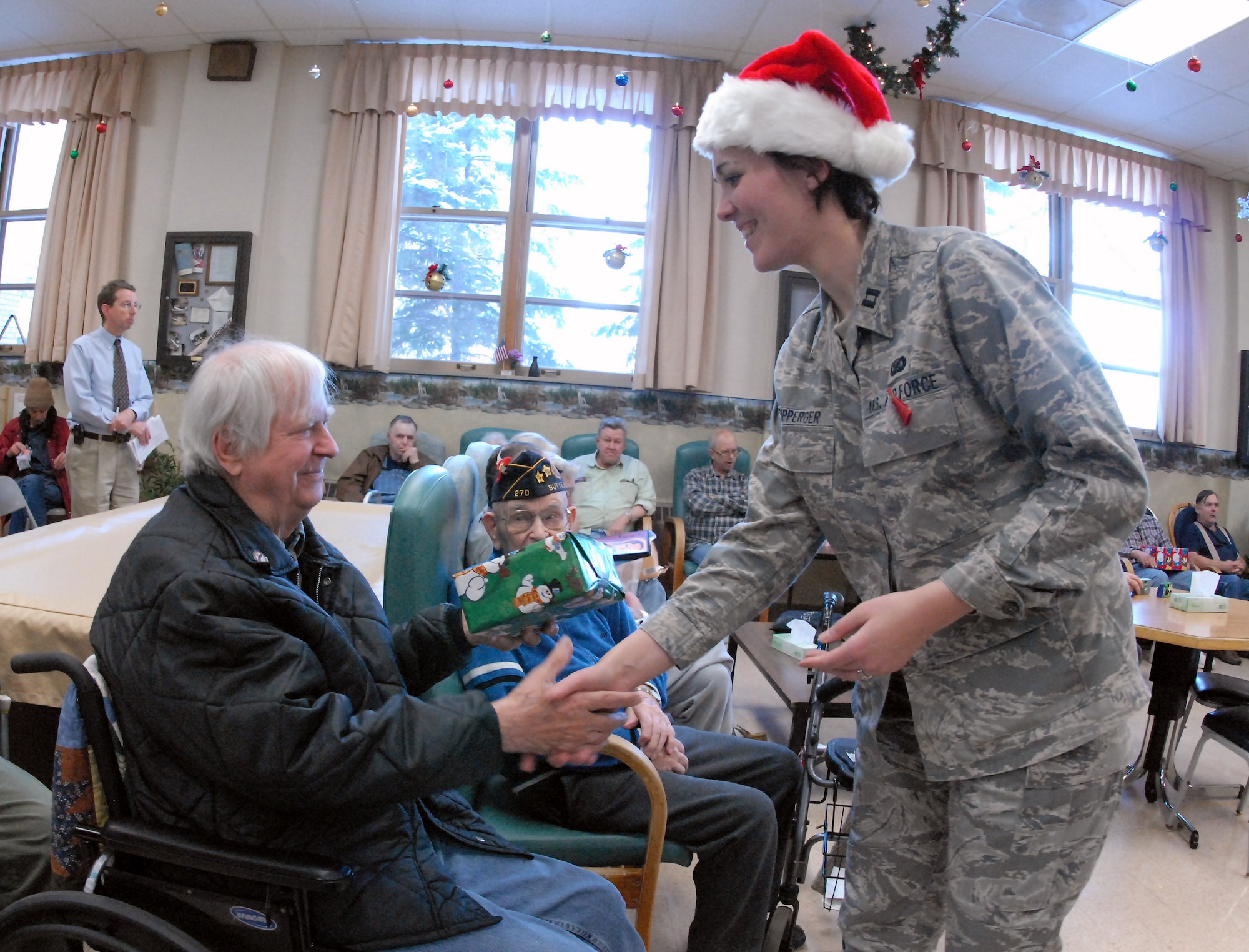 Capt. Penny Ripperger gives a Christmas gift to Navy veteran Howard Kvamme at the North Dakota Veteran's Nursing Home Dec. 10 in Lisbon, N.D. The gifts are given to veterans at the nursing home by the North Dakota Air and Army National Guard each December using funds raised through personal donations given by the North Dakota National Guard members. Captain Ripperger is the 119th Wing public affairs officer. (U.S. Air Force photo/Senior Master Sgt. David H. Lipp) 