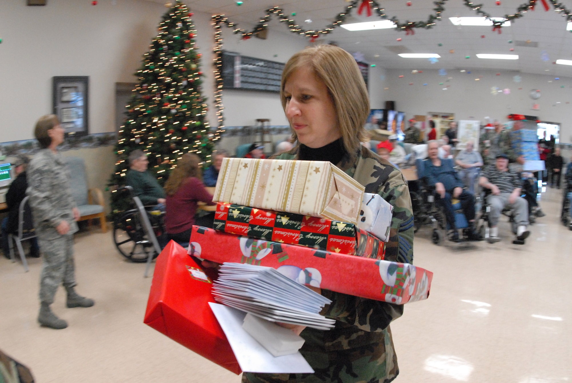 Senior Master Sgt. Sandi Renville carries Christmas gifts at the North Dakota Veteran's Nursing Home Dec. 10 in Lisbon, N.D. The gifts are given to veterans at the nursing home by the North Dakota Air and Army National Guard each December using funds raised through personal donations given by the North Dakota National Guard members. Sergeant Renville is assigned to the 119th Wing. (U.S. Air Force photo/Senior Master Sgt. David H. Lipp) 