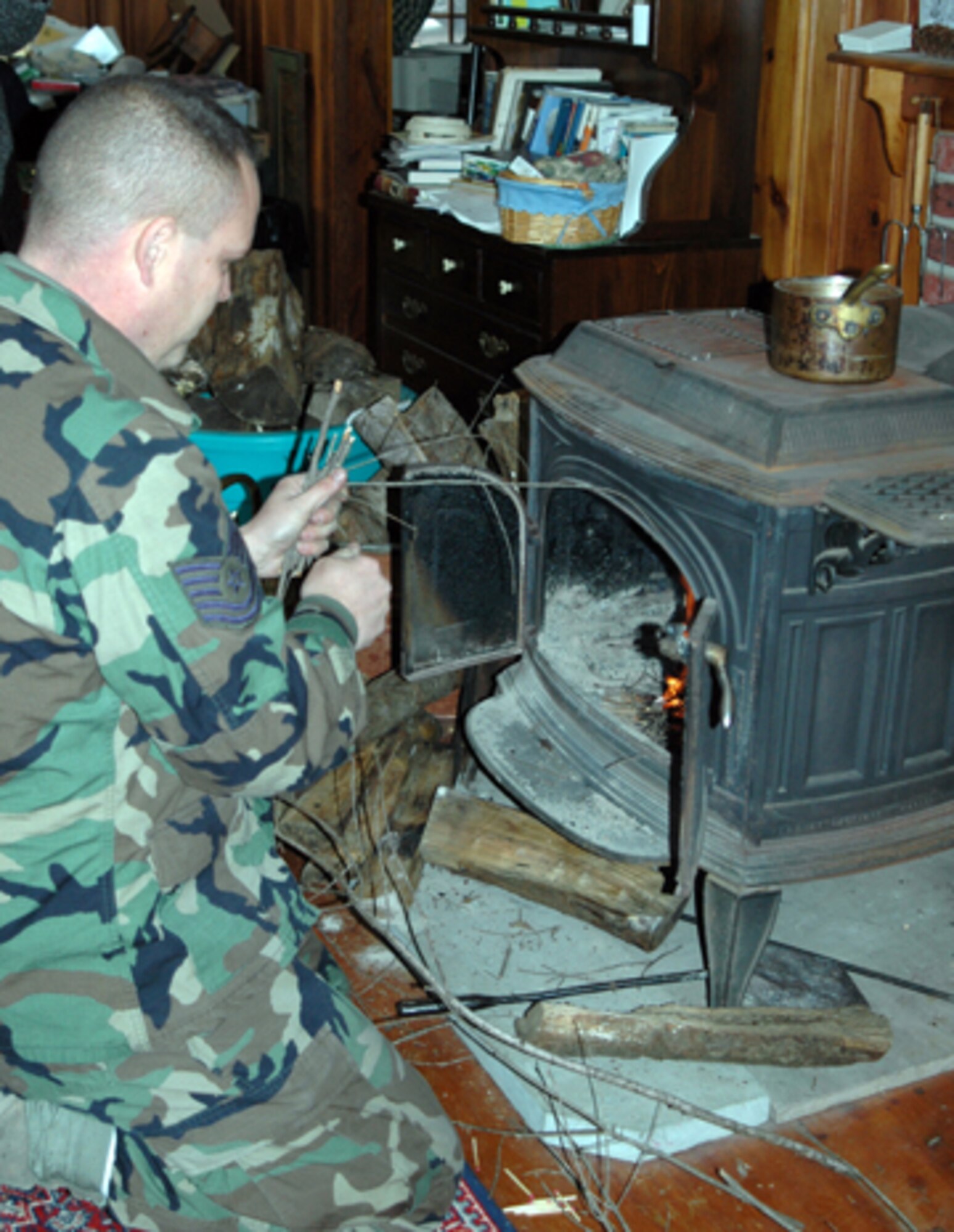 Tech. Sgt. John Bober of the 157th Air Refueling Wing, Pease Air National Guard Base, N.H. starts a fire for a local Stratham resident who was left without power due to the ice storm that hit the area six days earlier. (U.S. Air Force photo/1st Lt. Sherri Pierce) 