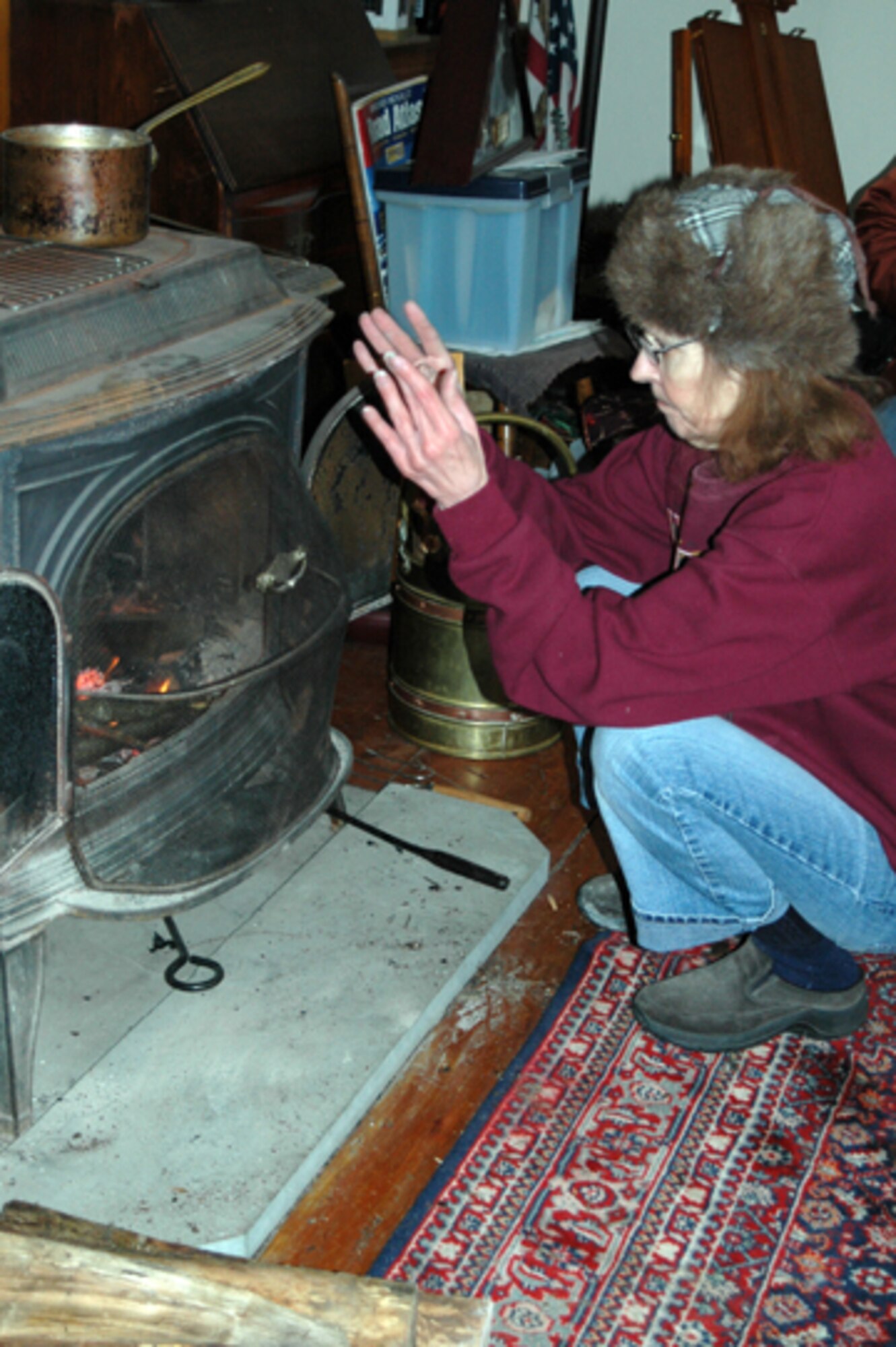 Patricia Olson of Stratham, N.H., warms herself by the fire.  The 157th Air Refueling Wing assisted the town with welfare checks during the ice storm that left Olson without power and heat for 6 days.  (U.S. Air Force photo/1st Lt. Sherri Pierce) 