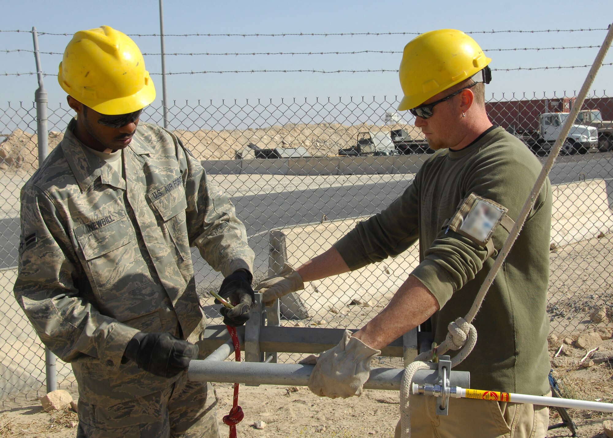 SOUTHWEST ASIA -- Airman 1st Class Delvon Newbill and Mr. Bobby Bezinque, 386th Expeditionary Communication Squadron Cable and Antenna Maintenance technicians, secure a Radio Over Internet Protocol (ROIP) antenna prior to hoisting it up a communications tower for installation on Dec. 15 at an air base in Southwest Asia. The 386th ECS Cable Maintenance shop provides command and control capabilities through installation, maintenance, fault isolation and reconstitution of fixed cable and wireless distribution systems, local area networks and wide area networks in support of tactical and strategic operations. Airman Newbill is deployed from Malmstrom Air Force Base, Mont. (U.S. Air Force illustration/Tech. Sgt. Raheem Moore)