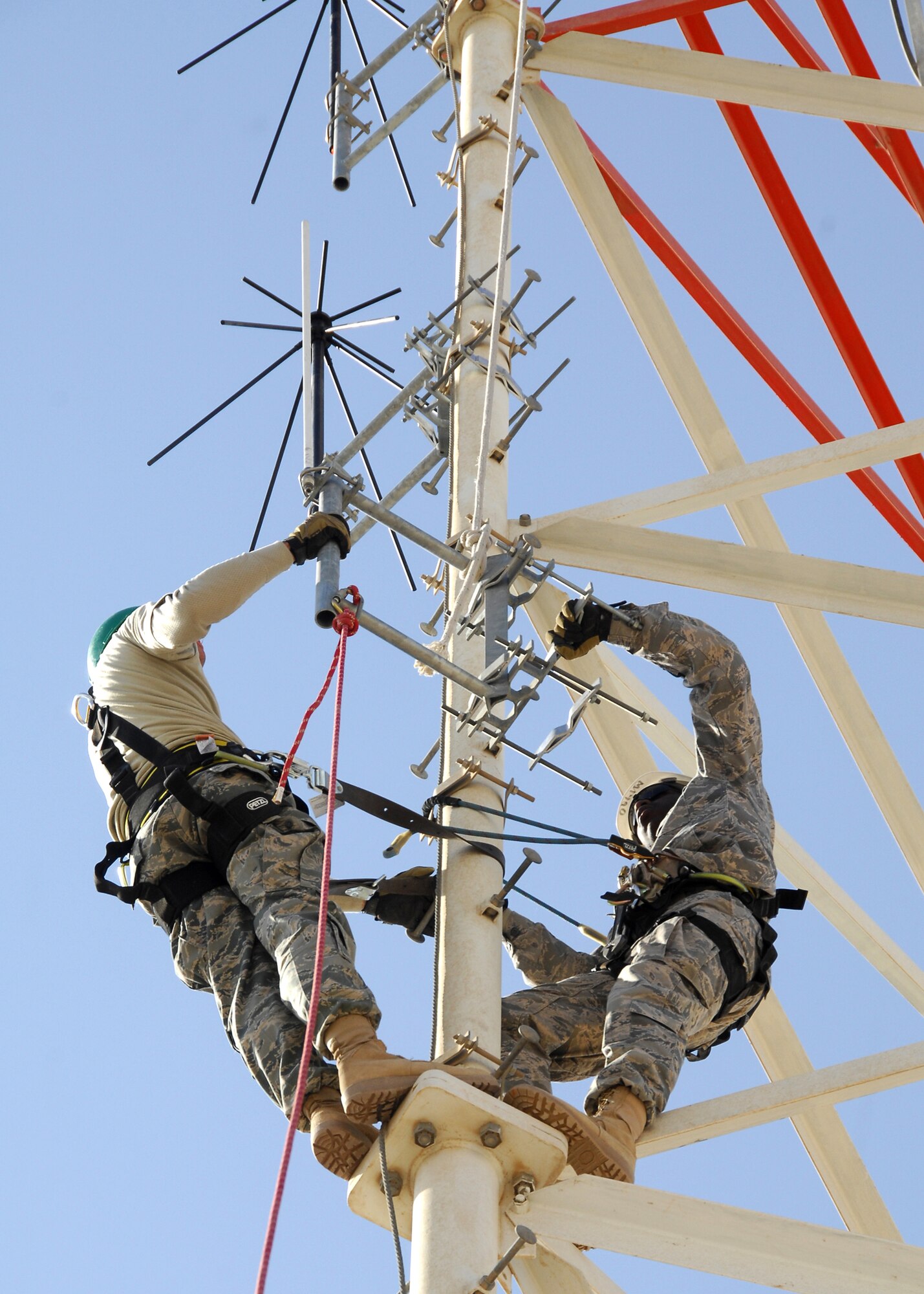 SOUTHWEST ASIA -- Staff Sgt. Ryan Trandell, left, and Senior Airman Lakendrick Fisher, 386th Expeditionary Communication Squadron Cable and Antenna Maintenance technicians, install a Radio Over Internet Protocol (ROIP) antenna to a communications tower on Dec. 15 at an air base in Southwest Asia. The 386th ECS Cable Maintenance shop provides command and control capabilities through installation, maintenance, fault isolation and reconstitution of fixed cable and wireless distribution systems, local area networks and wide area networks in support of tactical and strategic operations. Sergeant Trandell and Airman Fisher are deployed from Yokota Air Base, Japan. (U.S. Air Force photo/Tech. Sgt. Raheem Moore)