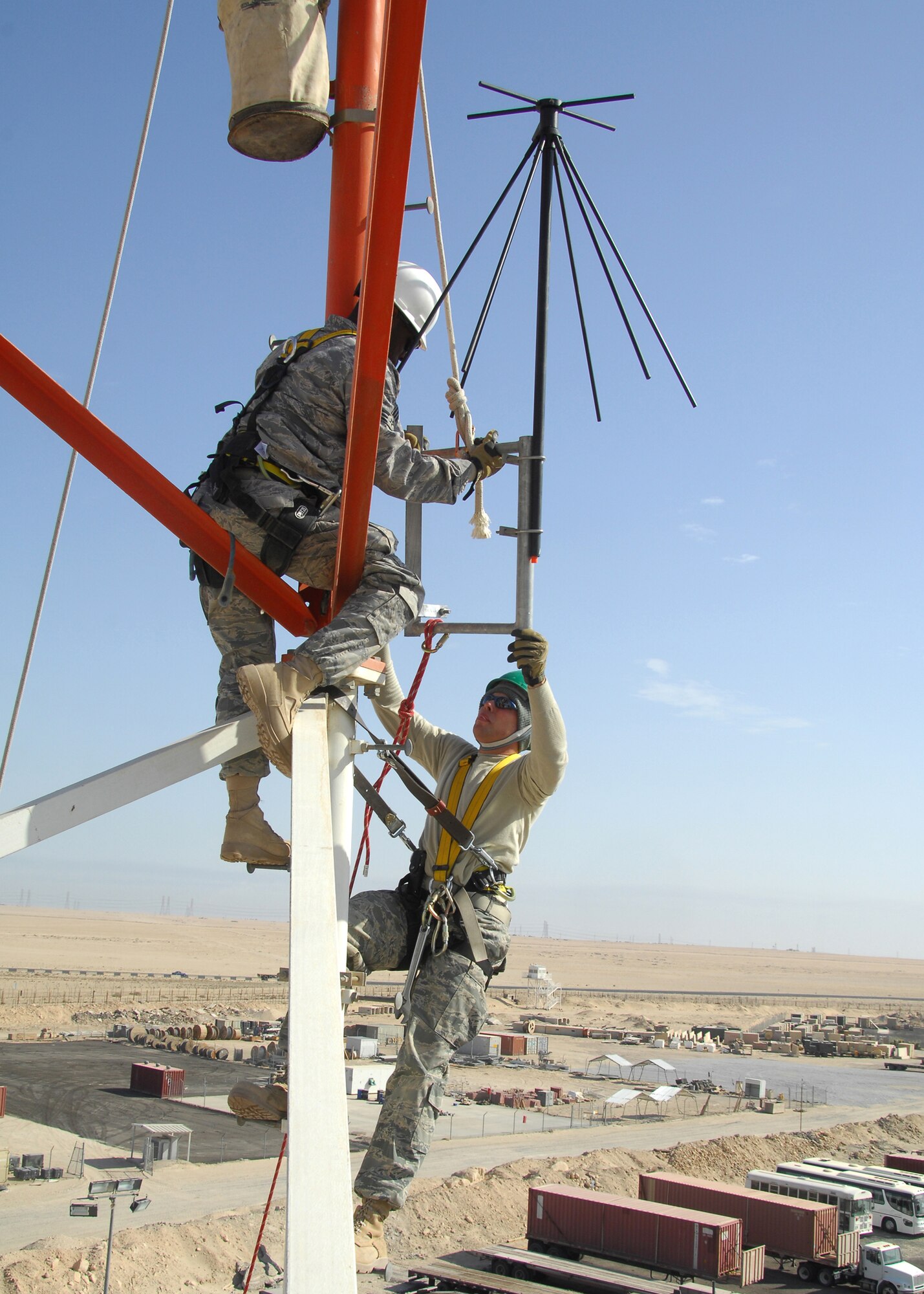 SOUTHWEST ASIA -- Staff Sgt. Ryan Trandell, bottom, and Senior Airman Lakendrick Fisher, 386th Expeditionary Communication Squadron Cable and Antenna Maintenance technicians, install a Radio Over Internet Protocol (ROIP) antenna on a communications tower on Dec. 15 at an air base in Southwest Asia. The 386th ECS Cable Maintenance shop provides command and control capabilities through installation, maintenance, fault isolation and reconstitution of fixed cable and wireless distribution systems, local area networks and wide area networks in support of tactical and strategic operations. Sergeant Trandell and Airman Fisher are deployed from Yokota Air Base, Japan. (U.S. Air Force photo/Tech. Sgt. Raheem Moore)