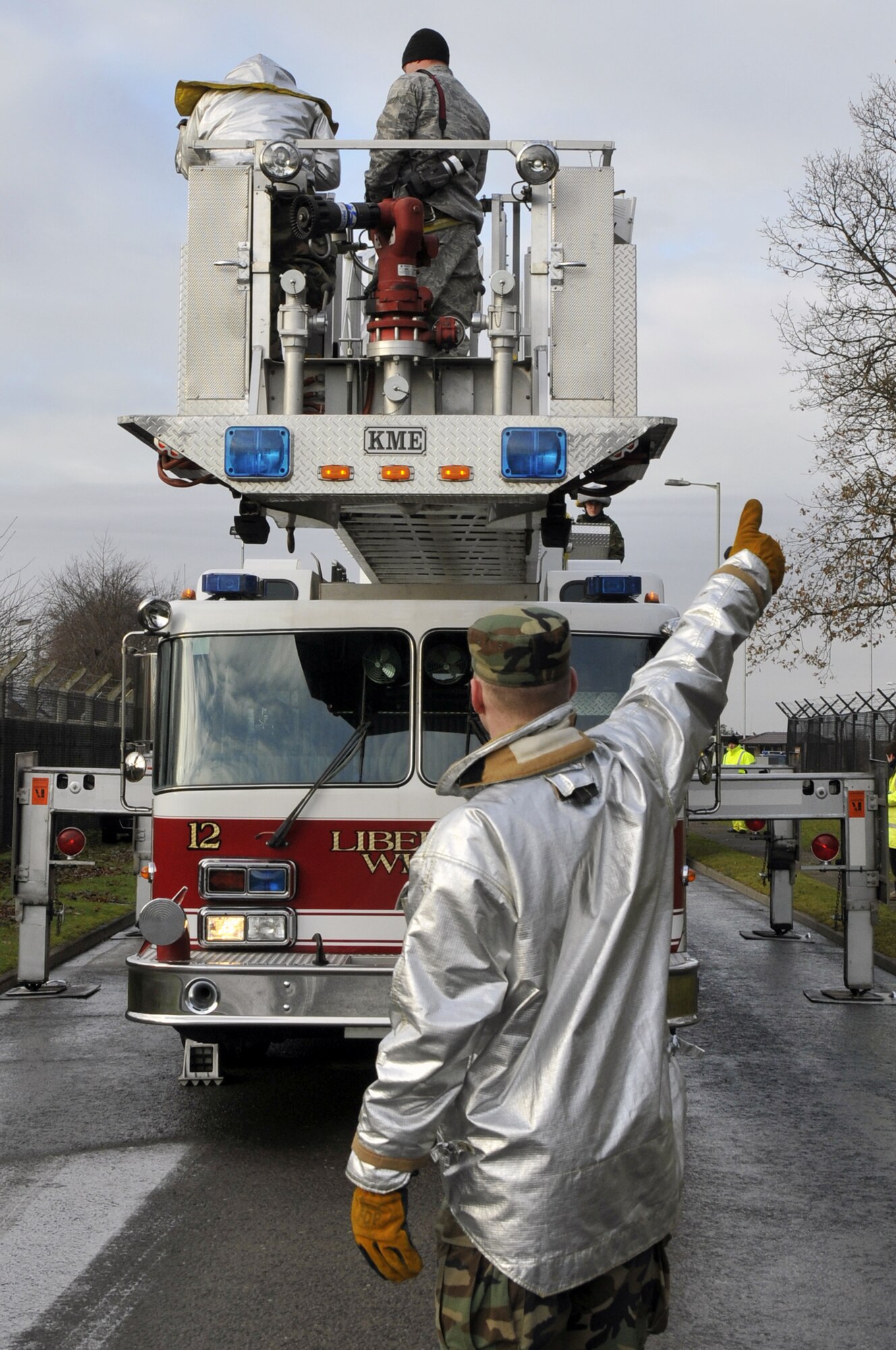 Staff Sgt. Henry Stratton 48th Civil Engineer Squadron fire fighter gives the all clear to Senior Airman Christopher Gaines, 48th Civil Engineer Squadron fire fighter, to continue lowering the ladder onto the cab of the ladder truck Dec. 12 at RAF Lakenheath, England. Liberty firefighters provided their platform ladder truck so aerial photos of the site can be taken. (U.S. Air Force photo by Airman 1st Class Perry Aston) 