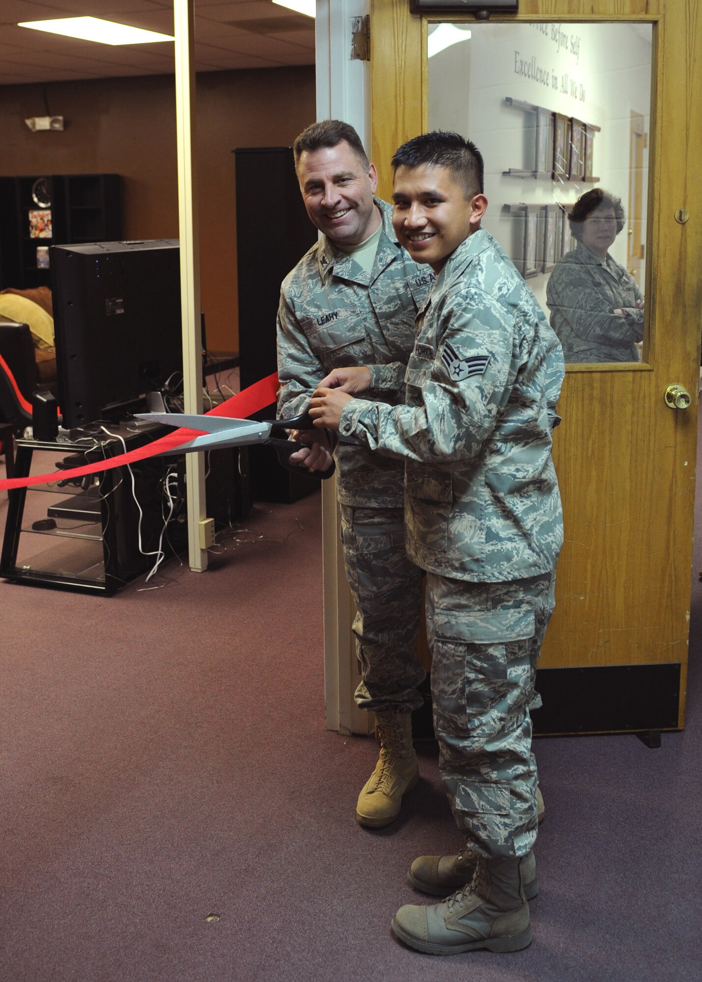 CANNON AIR FORCE BASE, N.M. -- Col. Timothy Leahy, 27th Special Operations Wing commander, and Senior Airman John Encomienda, 27th Special Operations Logistics Readiness Squadron, cut the ribbon at the new Airmen's Center located above the End Zone Dec. 19. The new Airman's Center has a movie room with reclining chairs, an overhead projector, surround sound, and a cyber cafe. There is also a second room devoted to gaming. (U.S. Air Force photo/Airman 1st Class Danielle Martin)