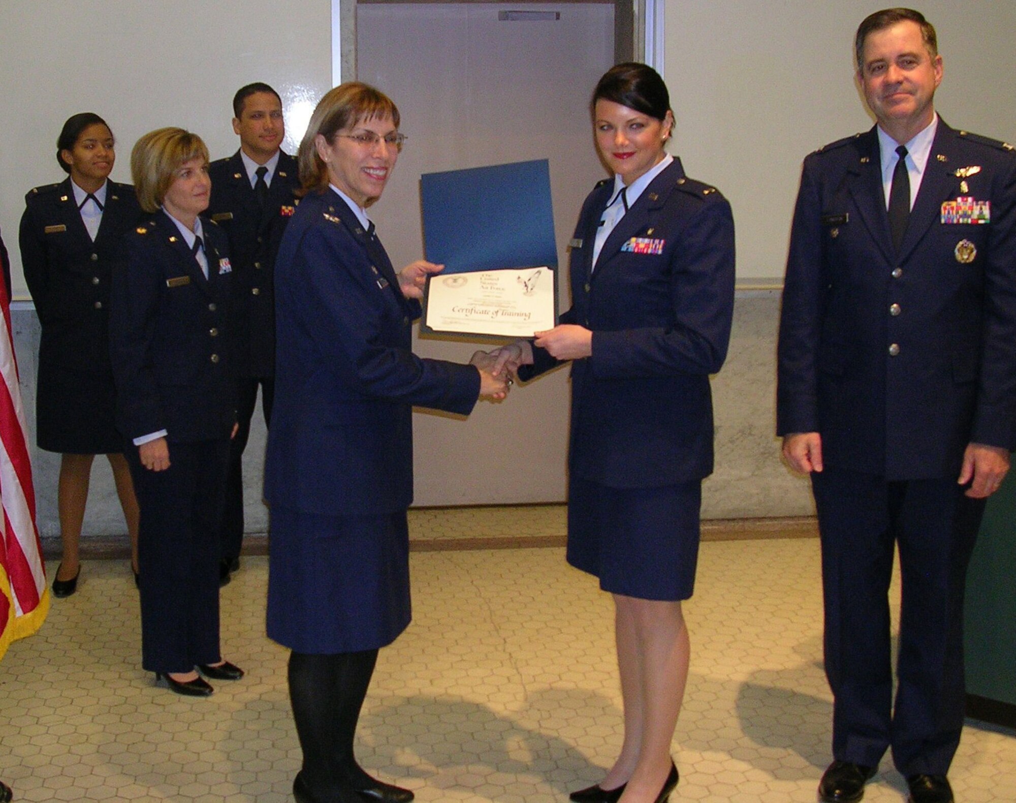 Col. Kimberly Slawinski, 88th Medical Group commander at Wright-Patterson Air Force Base, presents 2nd Lt. Candice Walter with her diploma for the Nurse Transition Program.  University Hospital Cincinnati and the Air Force have partnered to provide new registered nurses with the clinical skills and specialized training needed for deployment.  Assisting in the presentation are Col Thomas Langston, chief nurse at Wright-Patterson Medical Center (right) and Maj. Christine Berberick, chief of the Nurse Transition Program. (U.S. Air Force photo/Mike Frangipane) 