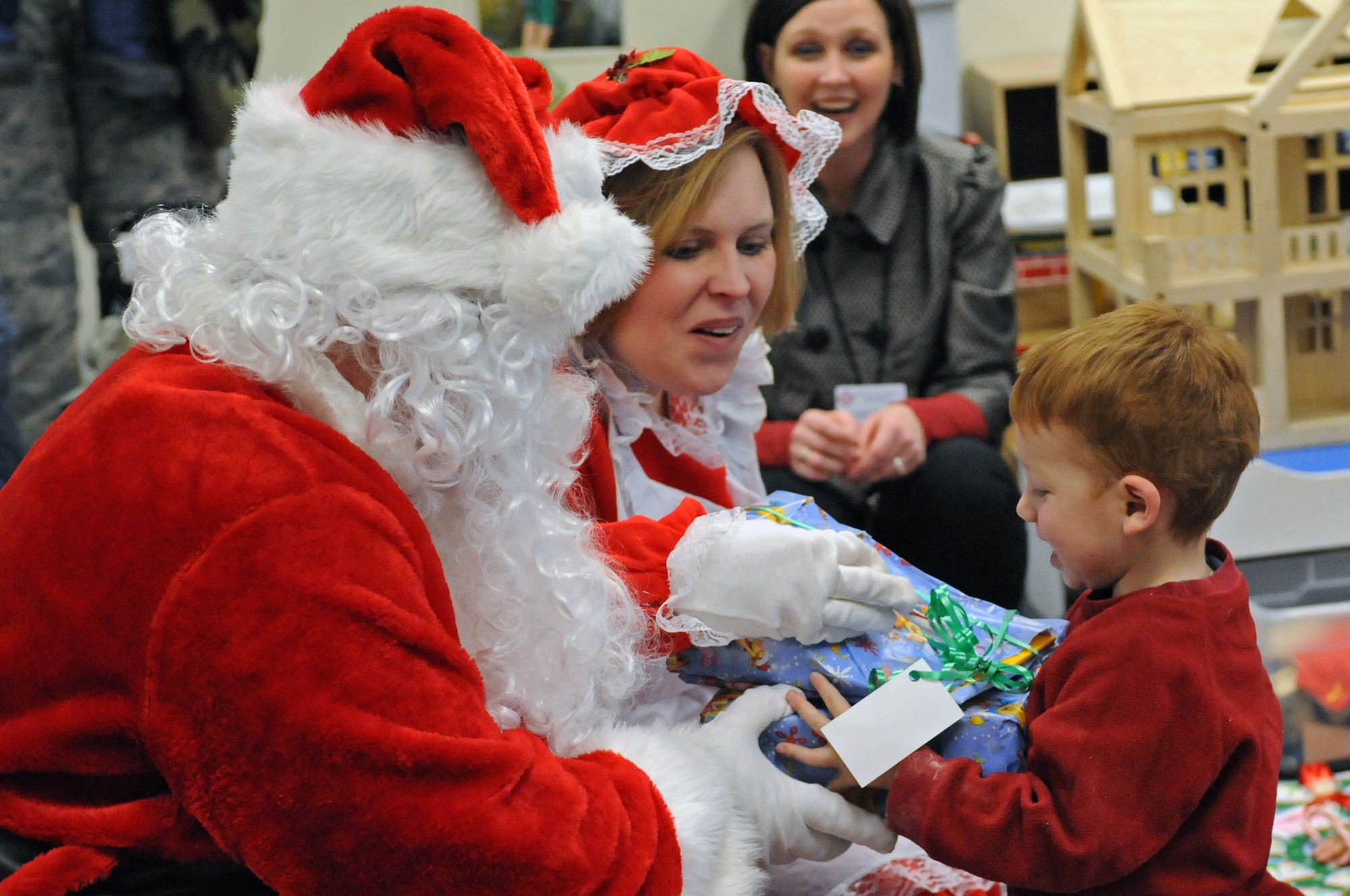 Santa and Mrs. Claus give Thad Anderson his present at the Youth and Family Services Child Care Center in Rapid City, S.D., Dec. 18, 2008. Students received many varieties of gifts due to the generosity of Ellsworth members and their families. (US Air Force photo/Airman 1st Class Corey Hook)
