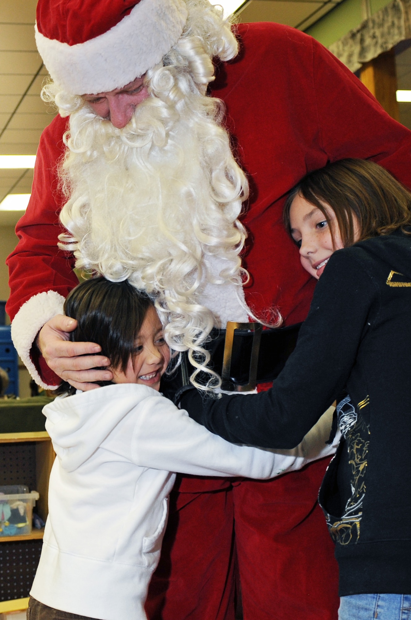 (Left to Right) Lily Whitehead and Victoria Weaver hug Santa at the Youth Center here, Dec. 18. The children ate food brought from families of Youth Center children and shaped cookies and crafts during Santa’s Visit. (US Air Force photo/Airman 1st Class Corey Hook)