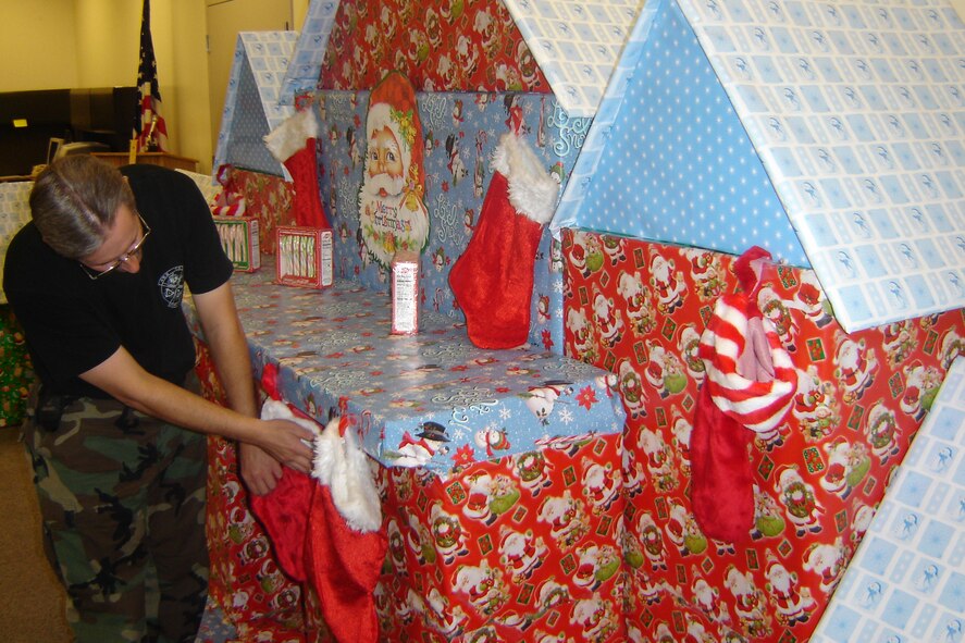 Senior Master Sgt.Mike Kastner, 452nd Civil Engineer Squadron, adjusts the stockings above the fireplace of Santa’s Village located inside the assembly room of the 452nd Civil Engineer Squadron at March Air Reserve Base, Calif. Senior Master Sgt. Kastner has been building Santa's Village for the past four years for the children of personnel at March during the squadron's annual Christmas party. (U.S. Air Force photos by Will Alexander)