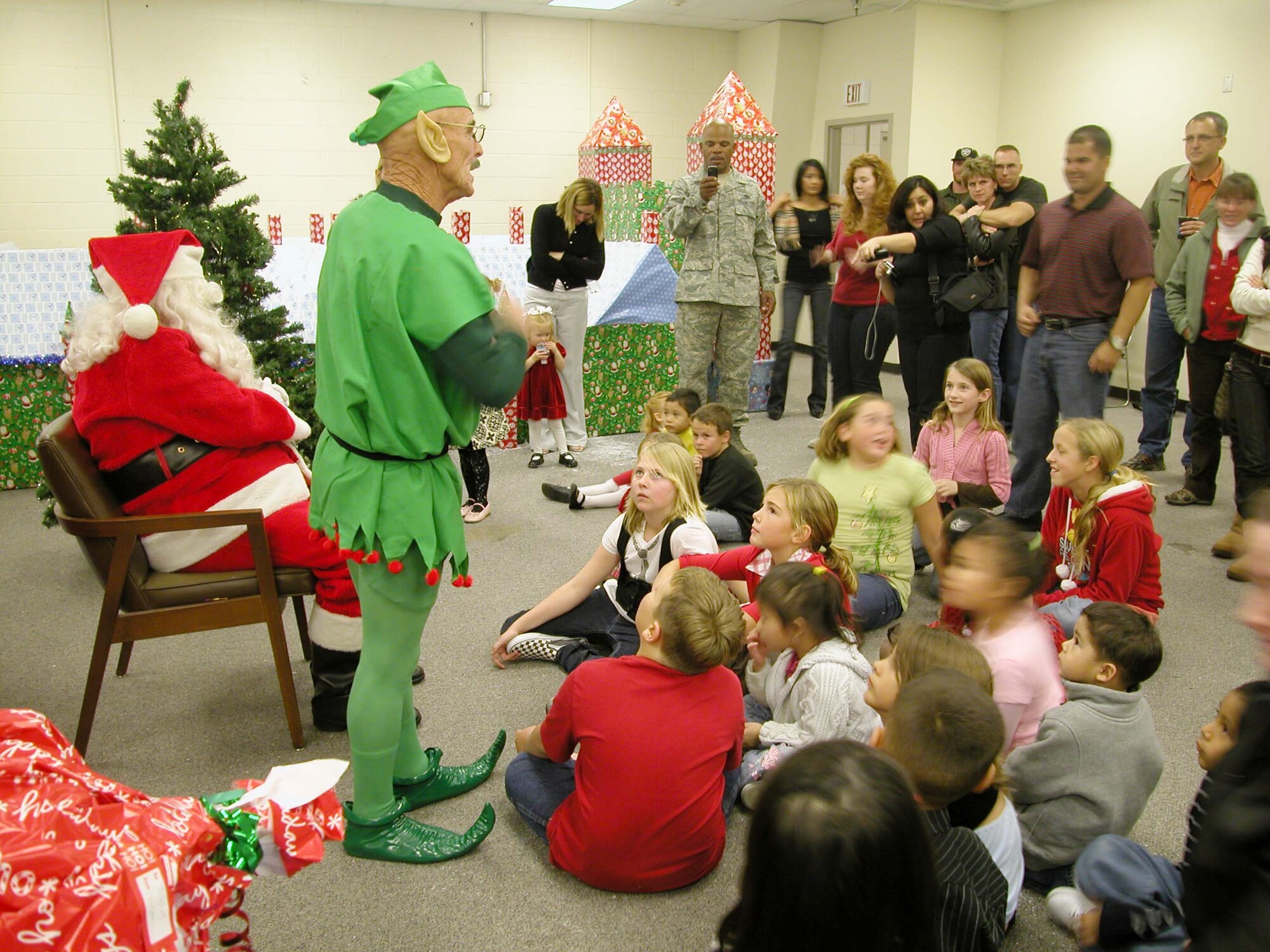 Santa’s elf (Christopher Dozois) calls out the names of children to come see Santa, Dec. 13, and to receive gifts during the 452nd Civil Engieer Squadron annual Christmas party at Santa’s Village in the unit’s assembly room at March Air Reserve Base, Calif.  Dozois, a retired master sergeant,  has played Santa’s elf for four years at the party.  Retired Chief Master Sgt. Donald Van Sickle has played Santa Clause at the party for the past 10 years.  (U.S. Air Force photo by Staff Sgt. Megan Crusher)
