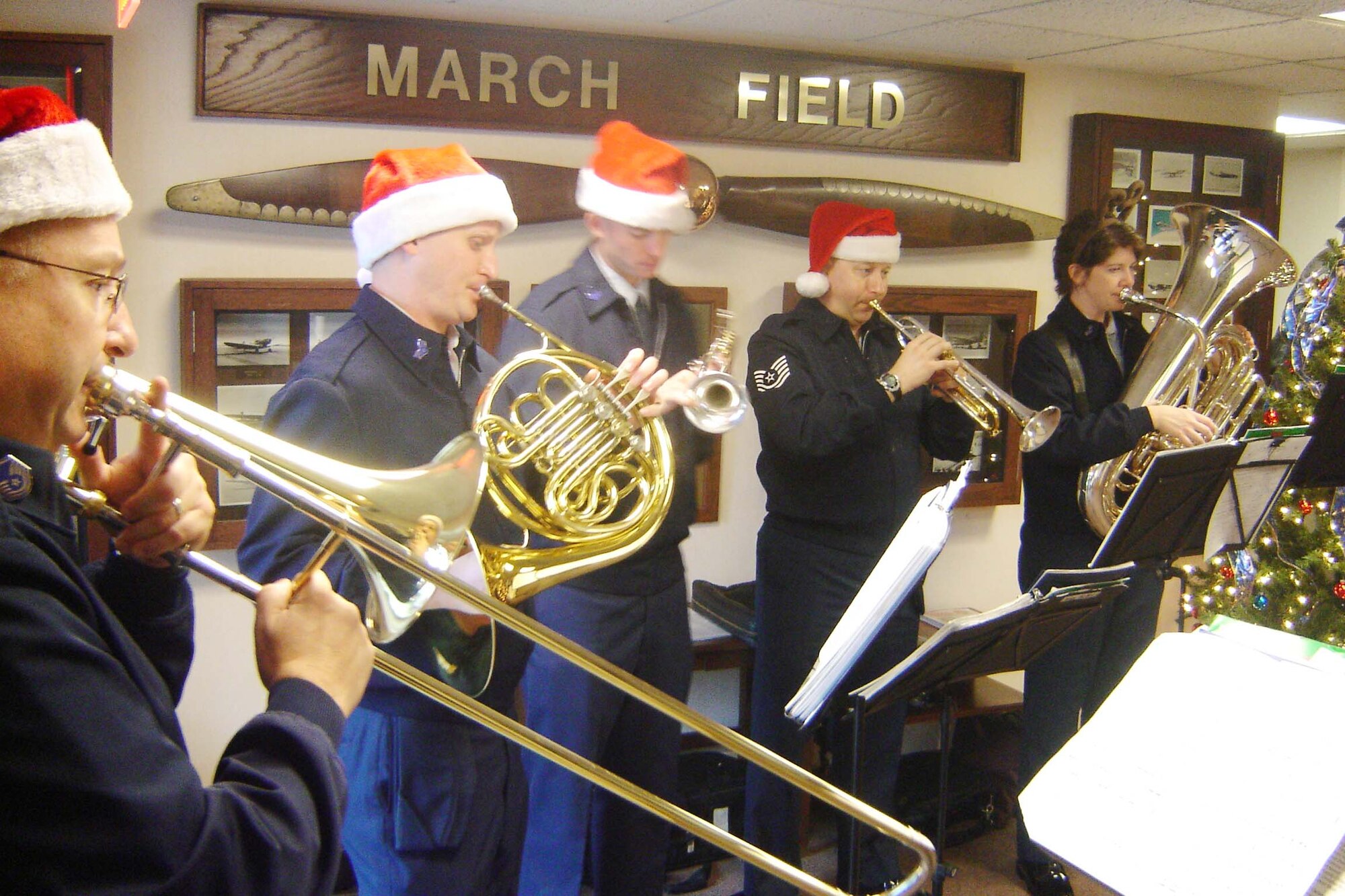 A brass quintet section of the U.S. Air Force Band of the Golden West from Travis AFB serenades personnel at March Air Reserve Base with Christmas music on a rainy Monday morning, Dec. 15.  (Left to right) Master Sgt. Cecil Benjamin,Senior Airman Edwin Ochsner,Senior Airman James Lantz,Tech. Sgt. Ed Shubert, and Senior Airman Jill Corbett shuttled to offices throughout March ARB to help put Team March in the Holiday spirit. The Band of the Golden West is comprised of 47 Airmen-musicians under the command of Major Keith H. Bland. The band supports 10 Air Force Bases, five Air Force Reserve Wings, and five recruiting squadrons in over 500 annual performances for 1.5 million listeners. (U.S. Air Force photo by Will Alexander)