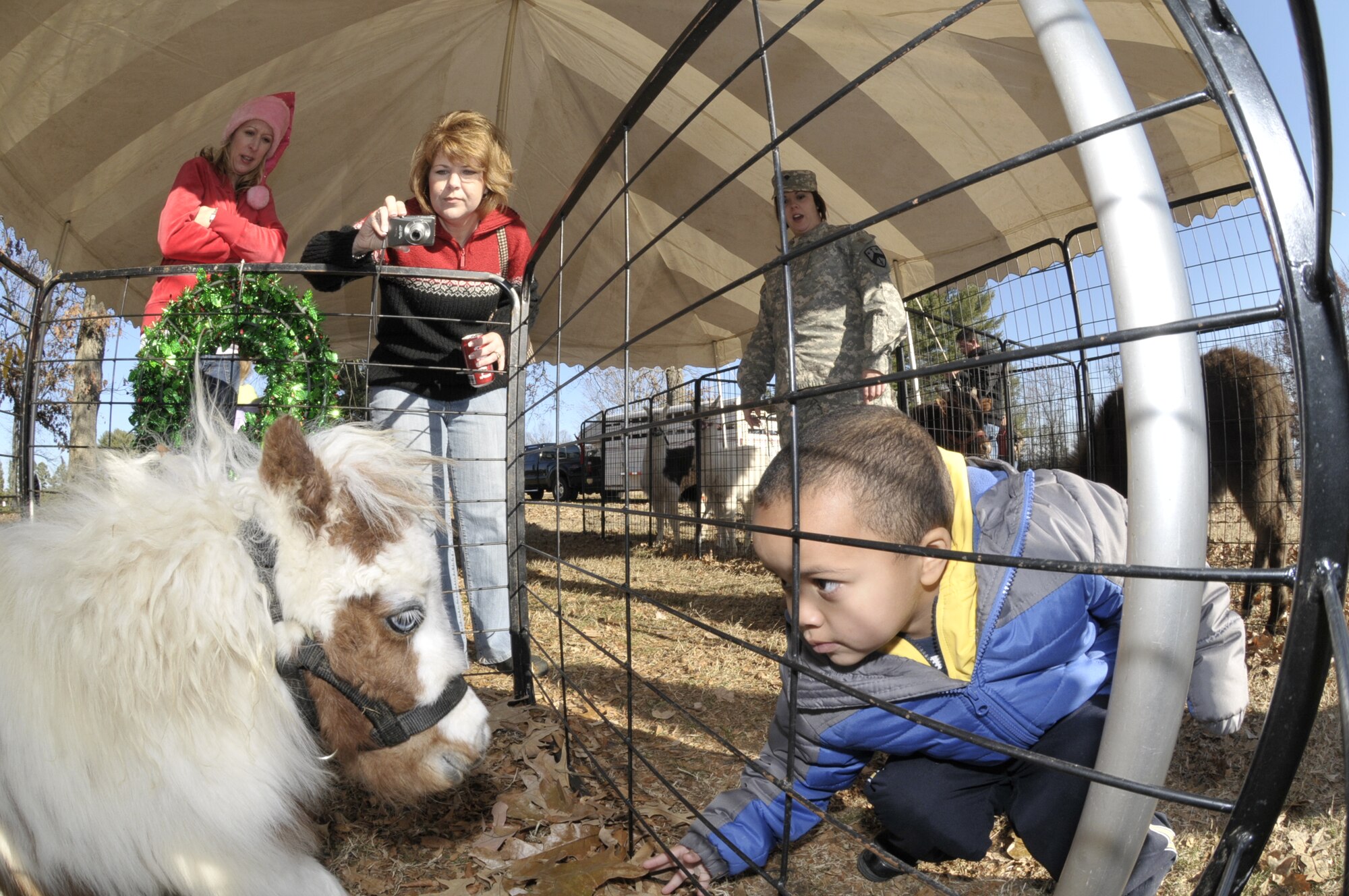 This little boy tries to make a friend in the petting zoo area at the annual Children’s Christmas Party at the Arnold Lakeside Club Dec. 7. (Photo by Rick Goodriend)