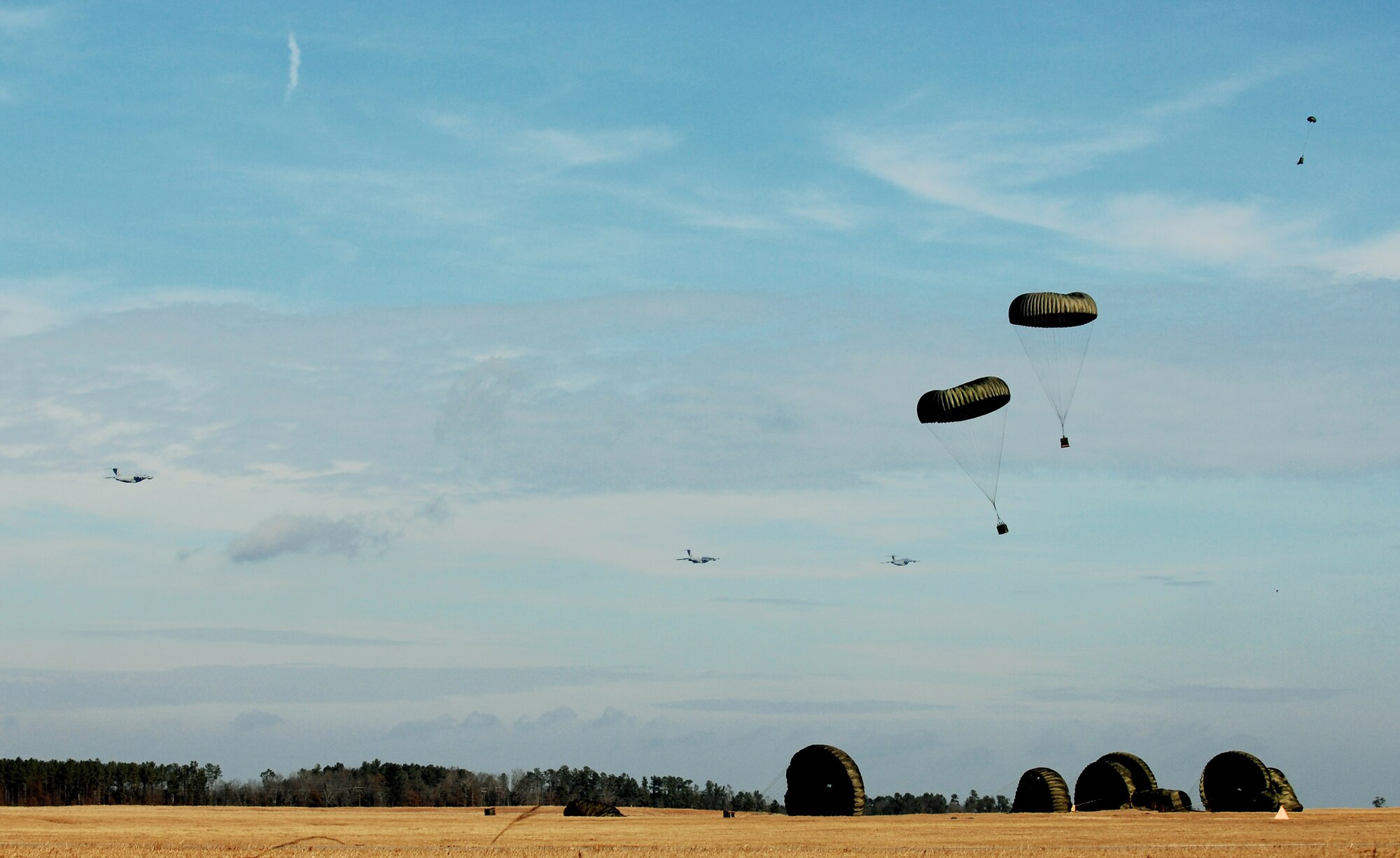 Globemaster IIIs from the 437th and 315th airlift wings drop cargo at a remote airfield during a strategic brigade airdrop exercise involving a 13-ship formation Dec. 18 from Charleston Air Force Base, S.C. C-17s must be able to meet the Army's goal of airdropping a brigade's worth of troops and equipment (about 3,250 Soldiers and 3,450 tons of equipment). Charleston AFB aircraft currently account for half of the Air Force strategic brigade airdrop requirement. (U.S. Air Force photo/Tech. Sgt. William Greer) 
