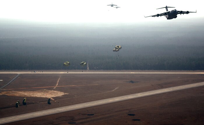 C-17 Globemaster IIIs from the 437th and 315th airlift wings drop cargo at a remote airfield during a strategic brigade airdrop exercise involving a 13-ship formation Dec. 18 from Charleston Air Force Base, S.C. C-17s must be able to meet the Army's goal of airdropping a brigade's worth of troops and equipment (about 3,250 Soldiers and 3,450 tons of equipment). Charleston AFB aircraft currently account for half of the Air Force strategic brigade airdrop requirement. (U.S. Air Force photo/Tech. Sgt. Jeremy Lock)