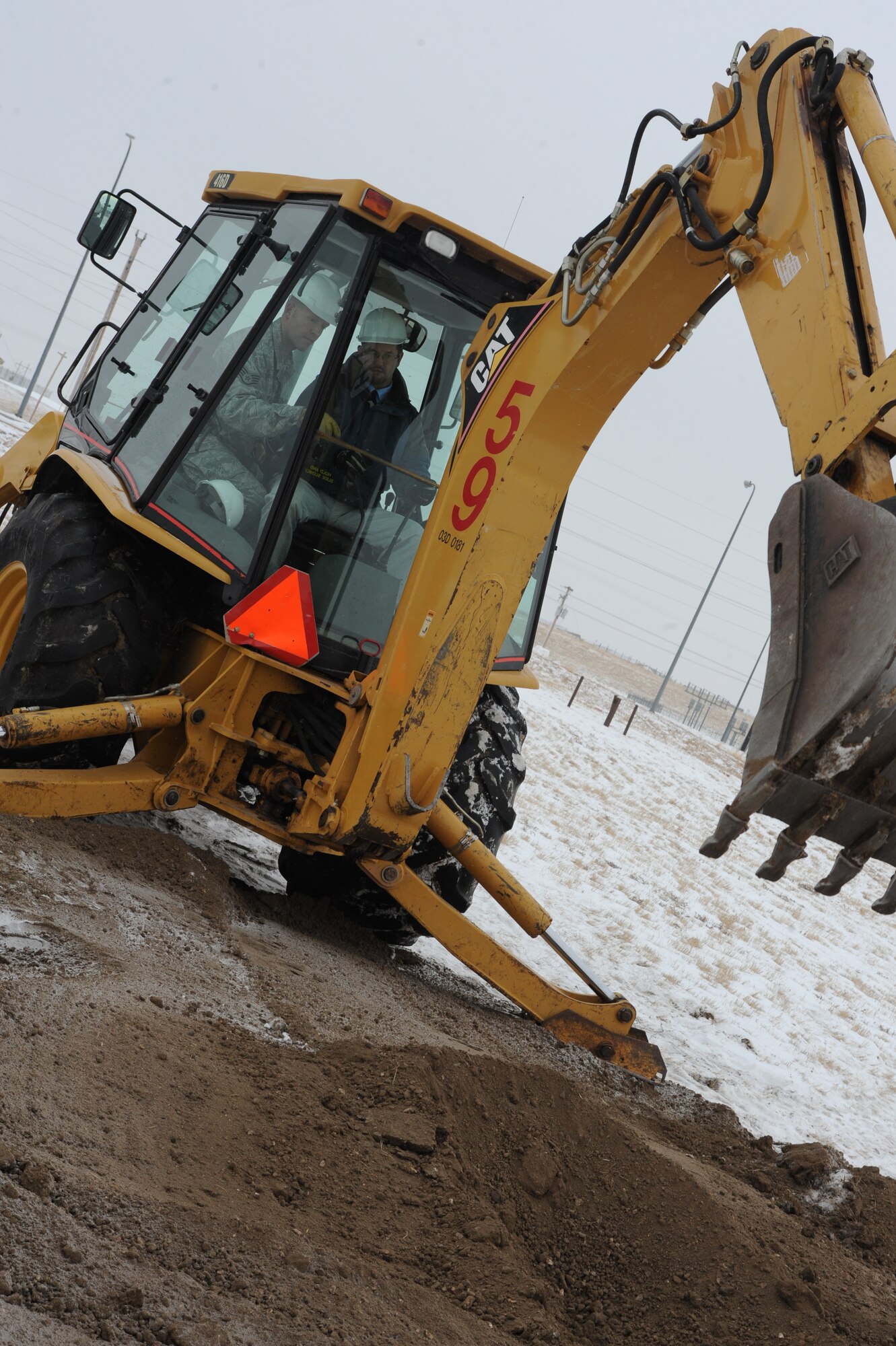 (Right) Darrell Shoemaker, Representative for Senator Tim Johnson, gains assistance from (left) Staff Sgt. Orlin Rhode, 28th Civil Engineer Squadron heavy equipment operator, as he prepares to scoop dirt during the 28th Civil Engineer Squadron headquarters ground breaking ceremony here, Dec. 18. The project has an estimated value of $16.6 million and is projected to be completed in July 2010. (U.S. Air Force photo/Airman 1st Class Adam Grant)