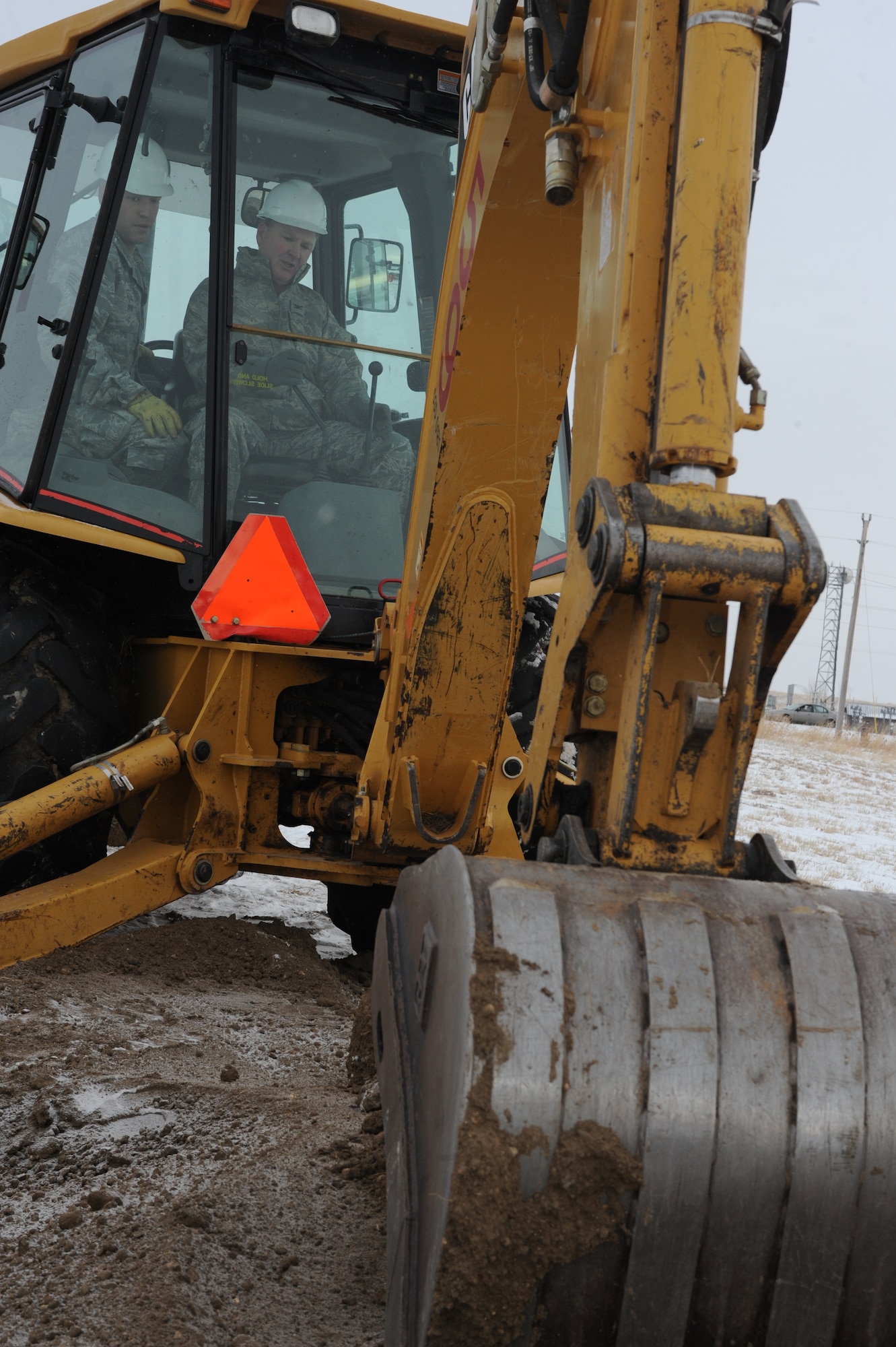 (Right) Col. Michael V. Yuill, 28th Mission Support Group commander, prepares to lift a scoop of dirt during the 28th Civil Engineer Squadron headquarters ground breaking ceremony while (left) Staff Sgt. Orlin Rhode, CES heavy equipment operator, assists here, Dec. 18. The project is planned to be completed July 2010 and will cost $16.6 million.  (U.S. Air Force photo/Airman 1st Class Adam Grant)