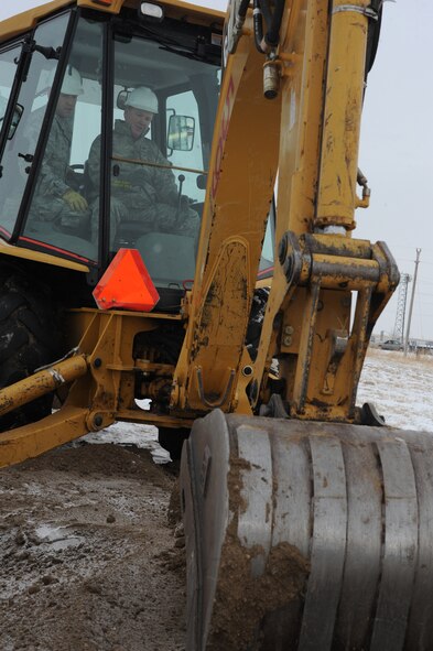 (Right) Col. Michael V. Yuill, 28th Mission Support Group commander, prepares to lift a scoop of dirt during the 28th Civil Engineer Squadron headquarters ground breaking ceremony while (left) Staff Sgt. Orlin Rhode, CES heavy equipment operator, assists here, Dec. 18. The project is planned to be completed July 2010 and will cost $16.6 million.  (U.S. Air Force photo/Airman 1st Class Adam Grant)