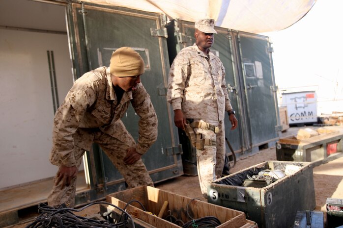 Gunnery Sgt. Timothy J. Newbill, a 37-year-old radio chief, and Lance Cpl. Lionel O. Carr, a 19-year-old battery noncommissioned officer, both with Headquarters and Service Company, Task Force 3rd Battalion, 7th Marine Regiment, Regimental Combat Team 5, sort through communications gear at Combat Outpost Ubaydi, Iraq, Dec. 18.  Each day presents a different task and challenge for the communication Marines.  With Marines tasked to numerous combat outposts and sections within the battalion, there's always work to be done.::r::::n::