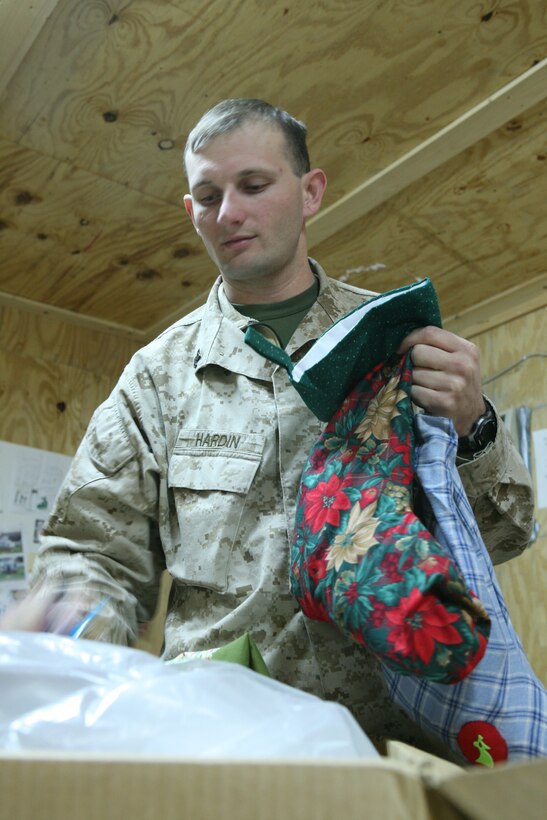 Petty Officer 2nd Class Gerad Hardin, religious programs specialist with Regimental Combat Team 5, sorts donated stockings to be distributed to Marines and sailors before Christmas. Hardin and Cpl. Alen Parkerson, chaplains assistant, collect and sort through scores of care packages daily so that RCT-5 personnel can readily take items they need.::r::::n::