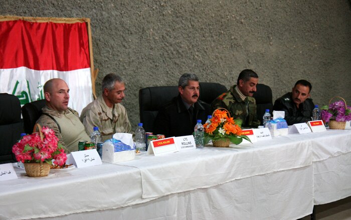 Lt. Col. Geoff Rollins (left), commanding officer, 2nd Battalion, 25th Marine Regiment, Regimental Combat Team 5, sits at the head table with Iraqi leaders from the Rutbah district in western al-Anbar province, Iraq, during the districtâ??s first-ever regional security meeting Dec. 20 at H3, an Iraqi Army outpost in the province.   Also pictured (from left to right) are: Saied, Rollinsâ?? interpreter; Qasum Marai Awwad, mayor of Rutbah; Col. Abbas Aiyed Raddad, commanding officer of the 3rd Battalion, 29th Iraqi Army Brigade; and Lt. Col Abdul Razak, the Rutbah district chief of police.::r::::n::