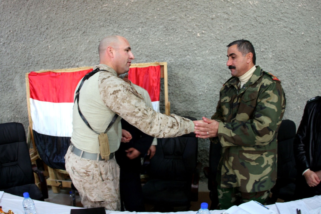 Lt. Col. Geoff Rollins, commanding officer, 2nd Battalion, 25th Marine Regiment, Regimental Combat Team 5, presents Col. Abbas Aiyed Raddad, commanding officer of the 3rd Battalion, 29th Iraqi Army Brigade with a commemorative coin at the conclusion of the district's regional security meeting Dec. 20.  This meeting at H3, an Iraqi Army outpost in western al-Anbar Province, was the first of several scheduled meetings for Iraqi and Coalition leadership.  ::r::::n::