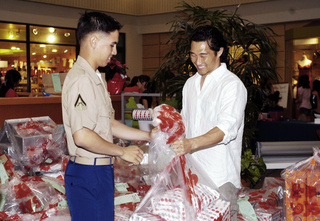 'Lost' actor Daniel Dae Kim hands a bag full of toys to Lance Cpl. Isaac Yuen at Kahala Mall here Dec. 22. Kim decided to make a generous donation to the Marine Corps Reserve's Toys for Tots campaign after hearing it is falling short of its goal this year, he said.