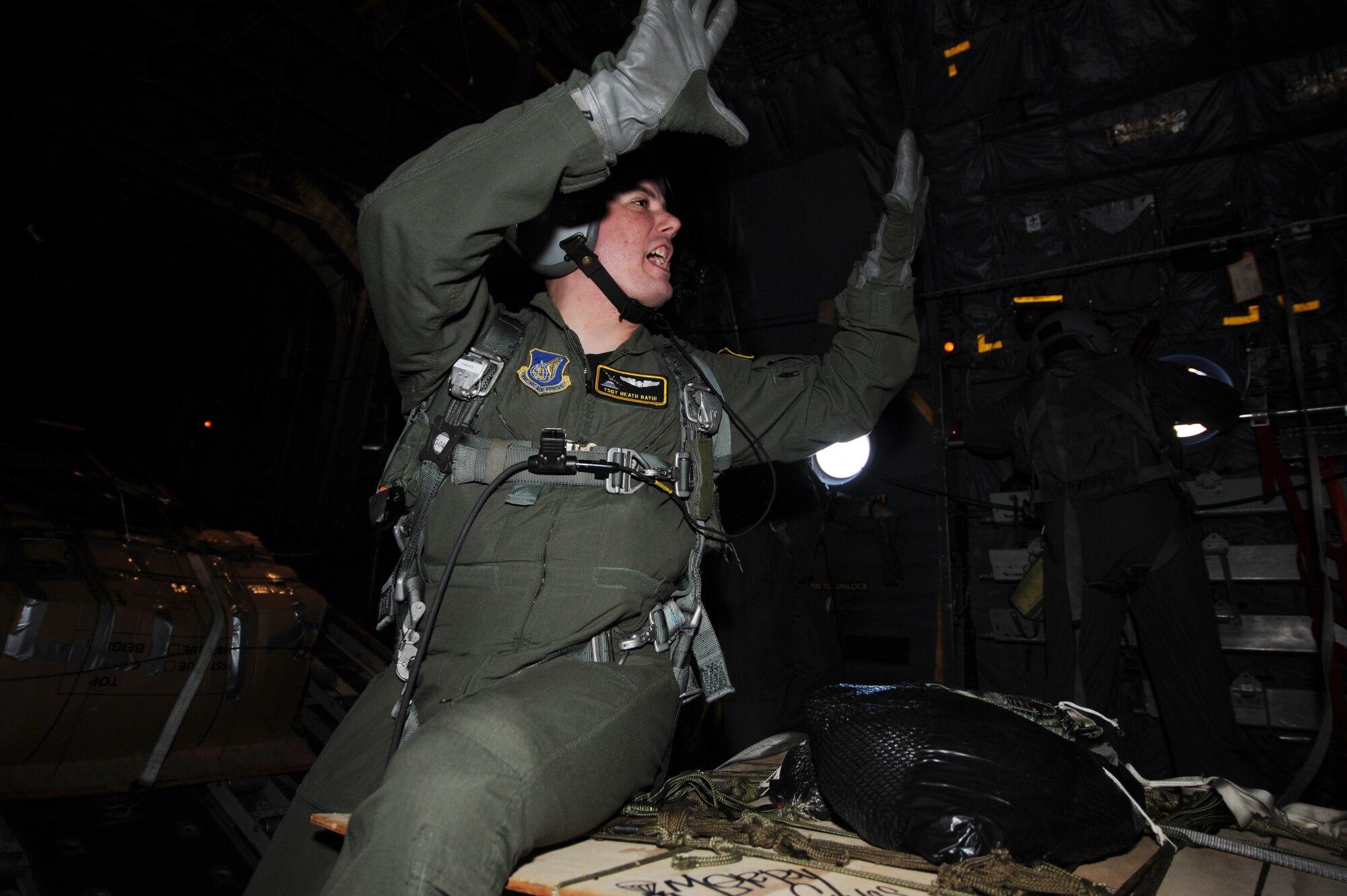 Tech. Sgt. Heath Bahyi signals to crew Dec. 19 that drop zone is 10 minutes out during Operation Christmas Drop. Airmen today continue the tradition, delivering supplies to remote islands of the Commonwealth of the Northern Marianas Islands, Yap, Palau, Chuuk and Pohnpei. Through military and local community support, Operation Christmas Drop has collected tens of thousands of donated items and raised more than $30,000 in support of the operation. Sergeant. Bahyi  is a loadmaster from the 36th Airlift Squadron, Yokota AB, Japan. (U.S. Air Force photo/ Master Sgt. Kevin J. Gruenwald) released