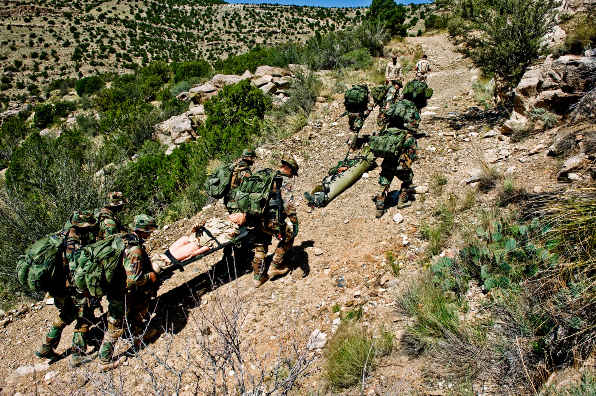 Carrying a "patient" up a mountain path for nearly two miles, Airmen 1st Class Mark Lillmars and Jared Stidham labor in the 100-degree New Mexico heat. As part of a training exercise, the pararescue students had to get the heavy mannequin to a waiting CV-22 to medevac their "injured patient."  (U.S Air Force Photo by Tech Sgt. Matthew Hannen)