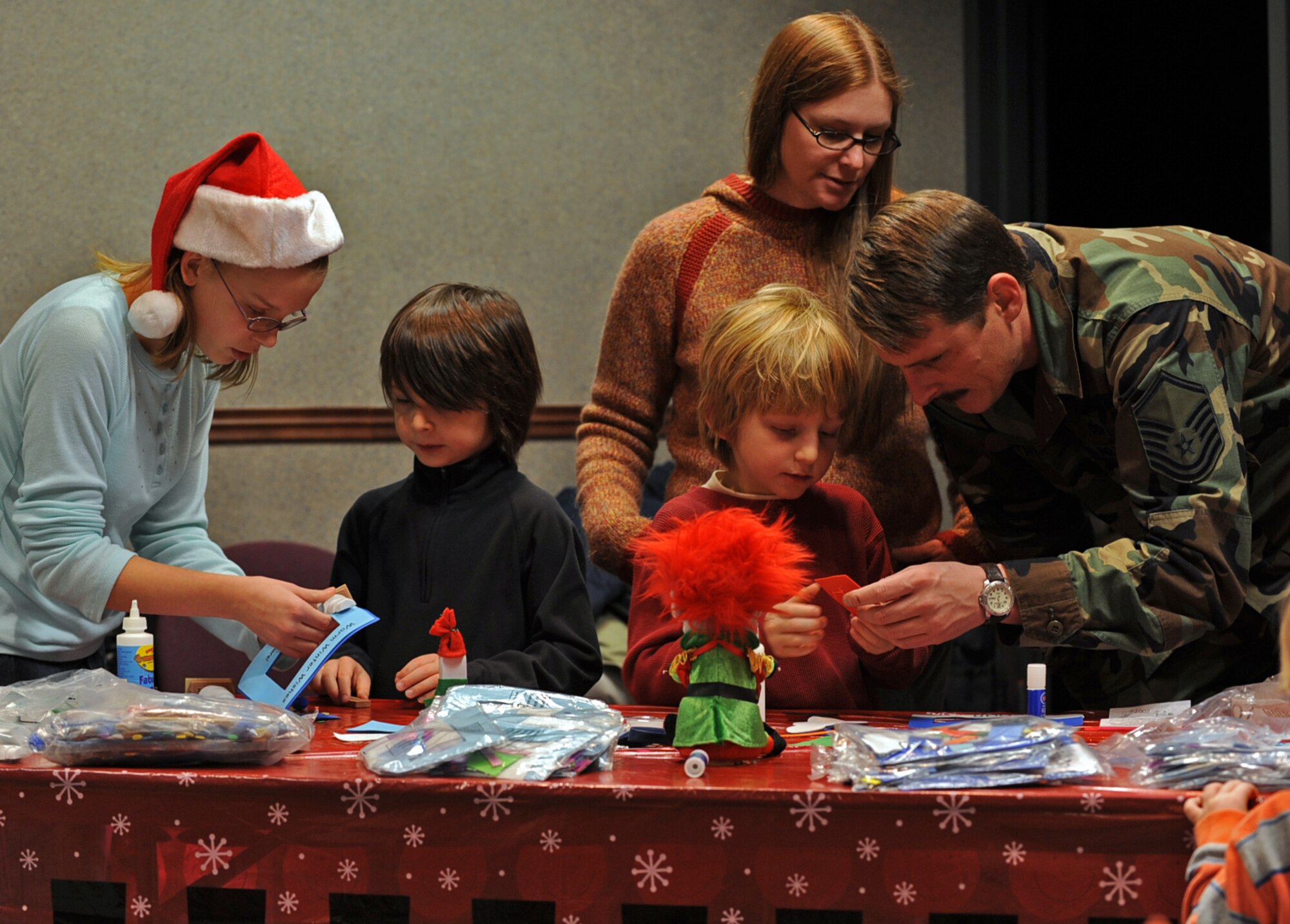 Master Sgt. Daniel McCarthy helps his 6-year-old son, Aiden, create a holiday craft at the 931st Air Refueling Group's annual Christmas party. Sergeant McCarthy's wife, Erin, watches while Amanda Hughes, a party volunteer, helps their other son, 7-year-old Liam, make his own craft. Amanda is the 12-year-old daughter of Tech. Sgt. Shannan Hughes, assistant chief of the 931st Military Personnel Flight's education and training office. Sergeant McCarthy is a communication and navigation technician for the 931st Aircraft Maintenance Squadron. (U.S. Air Force photo/Tech. Sgt. Jason Schaap)