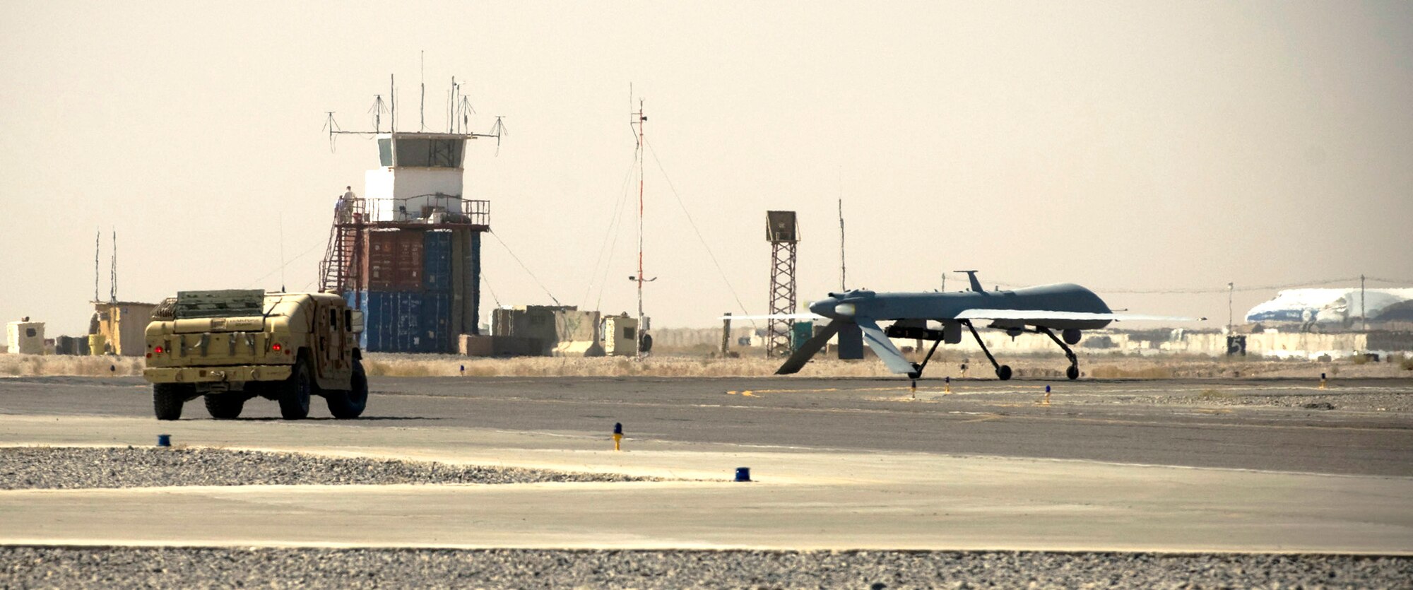 A security forces Humvee escorts an MQ-1 Predator onto the runway Oct. 26 at a base in southern Afghanistan. Due to the small size of the aircraft and how unfamiliar many pilots are with it at the NATO-controlled airfield, security forces must escort the Predator to prevent potential mishaps. (U.S. Air Force photo/Staff Sgt. Samuel Morse) 
