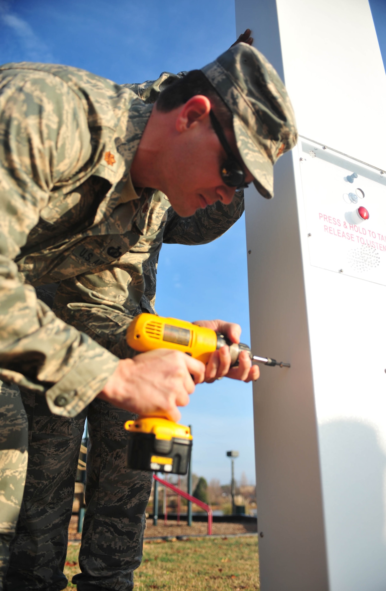 SHAW AIR FORCE BASE, S.C. -- Maj. James A. Hageman, 20th Contracting Squadron commander, drills the final securing bolt in the base of the new emergency system.  In case a caller is distressed, upon activation, a digitally stored voice will automatically transmit over the callbox radio channel to let responding personnel know the exact location of the callbox. (U.S. Air Force photo/Staff Sgt. Patrick Mitchell)