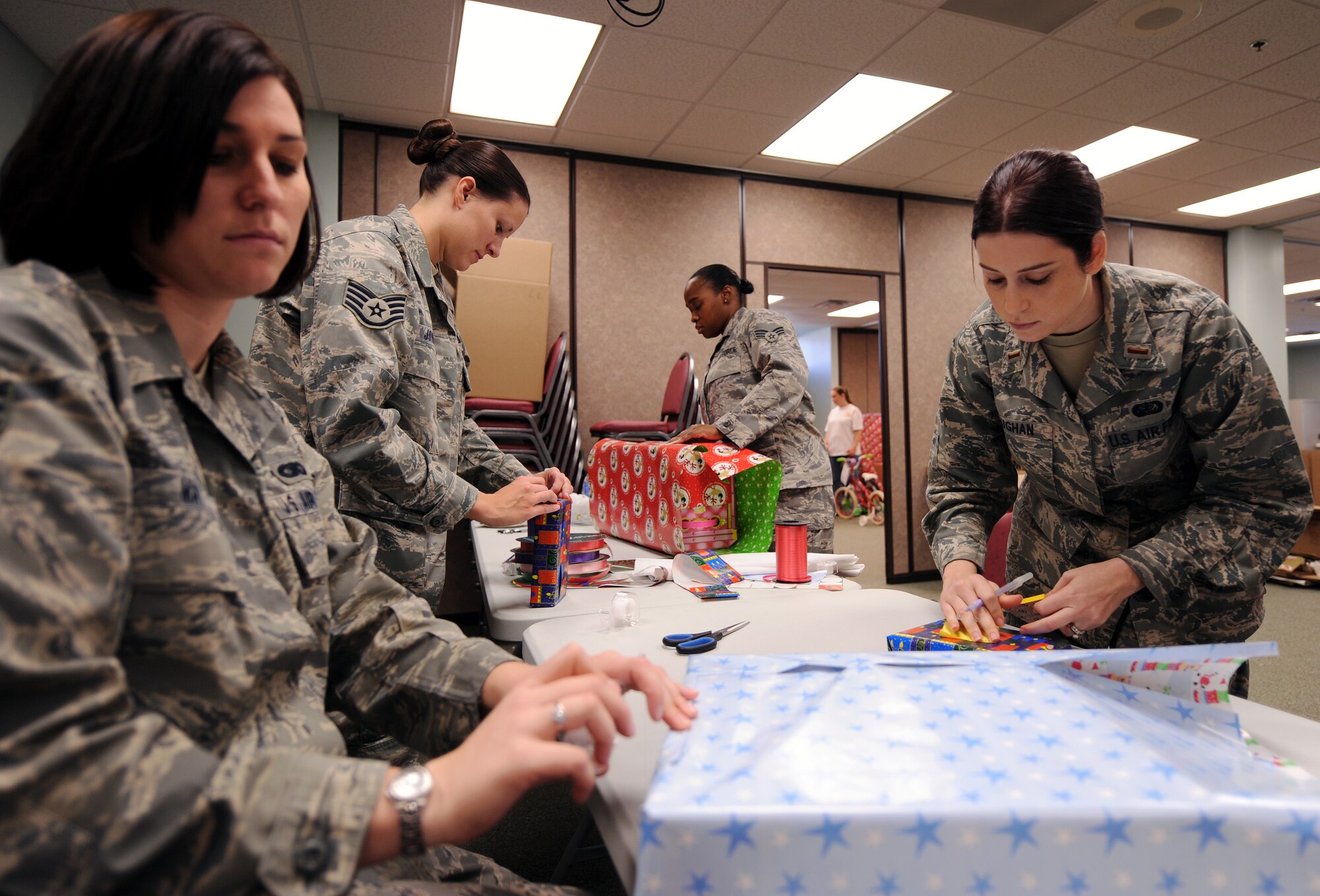 MOODY AIR FORCE BASE, Ga. -- Airmen volunteer their time by wrapping presents for the Adopt-a-Family event at the Chapel Dec. 18 here. The Adopt-a-Family program consists of squadrons, units and individuals who anonymously adopt less fortunate families and foster children during the holidays and provide them with gifts. (U.S. Air Force photo by Airman Joshua Green)