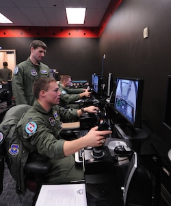 Lieutenants Jason Ruiz (front), Brad Delloiacano (standing) and Kyle Durch (back) practice using targeting pods on simulated attack aircraft during lab instruction at the Unmanned Aircraft Systems Fundamentals Course Dec. 16. (Photo by Rich McFadden)