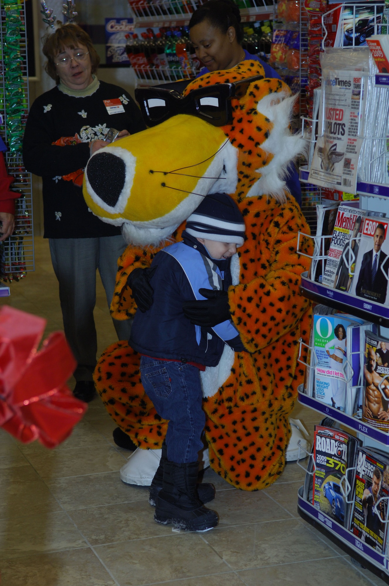 MINOT AIR FORCE BASE, N.D. -- Toby Wools, son of Tech. Sgt. Dusty Wools, 5th Maintenance Squadron, hugs Chester Cheetah at the grand opening of the new base shoppette here Dec. 19. The new, state-of-the-art $17 million facility is more than 19, 000 square feet and includes 24-hour operation, a replacement of the existing Army and Air Force Exchange Service service station and an AAFES-operated car wash. (U.S. Air Force photo by Senior Airman Cassandra Jones)