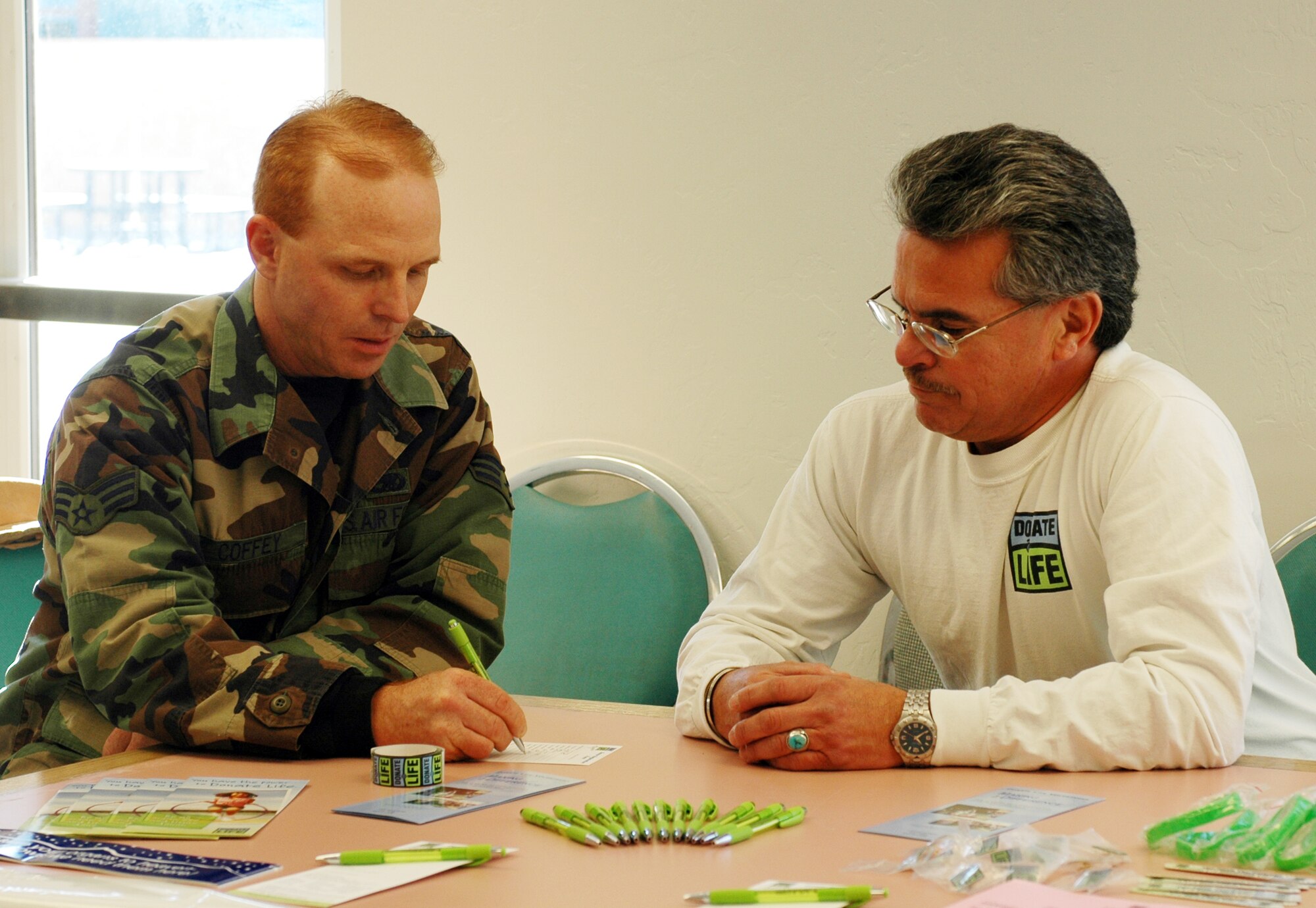 John Salazar Jr., volunteer for the Donor Network of Arizona, assists 162nd Maintenance Squadron member Senior Airman Scott Coffey with filling out a donor application during the December drill. John is a cornea recipient benefiting from the donor network and he’s the son of retired 162nd member John Salazar. (Air National Guard Photo by Staff Sgt. Desiree Twombly)