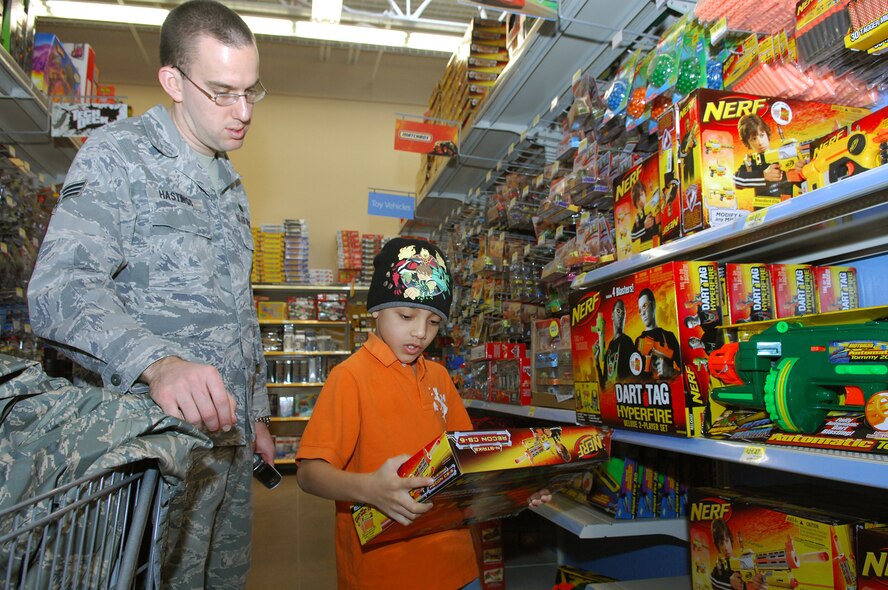 MINOT, N.D. - Senior Airmen James Hastings, 91st Missile Security Forces Squadron, helps Xavier Falcon, a 4th grader at Sunnyside Elementary School, pick out a dart gun during the 6th annual Shop with a Cop at Walmart here Dec 21. Children participated in four activities throughout the year in the Companions for Children program to earn the shopping spree. This year 52 children each received $150 in gift cards to buy gifts for themselves or family members. (U.S. Air Force photo by Tech. Sgt. Linda Miller)