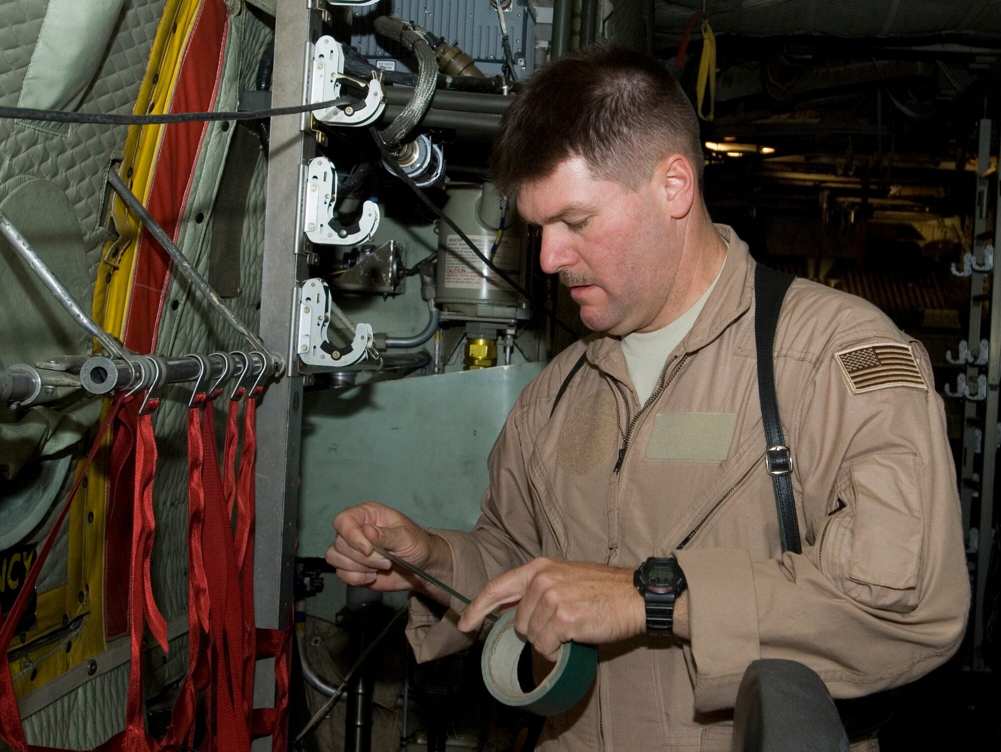 Navy Chief Petty Officer Dan Boyles, an avionics technician from the Expeditionary Combat Readiness Center at Naval Station Norfolk, Va. assigned to the 777th Expeditionary Airlift Squadron, Joint Airborne Battle Staff detachment, attaches tape to a piece of equipment used to keep track of their current location while in the air at Joint Base Balad, Iraq, Dec. 6. Boyles, a native of Winter Park, Fla. is a mission commander of a team who assist convoys when they have communication problems and need help. (U.S. Air Force photo/Tech. Sgt. Erik Gudmundson)		