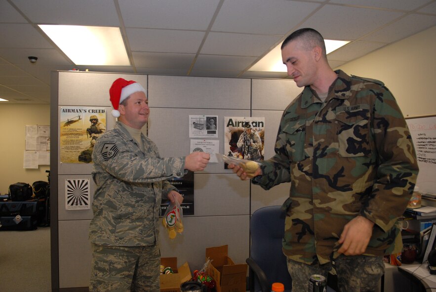 KUNSAN AIR BASE, Republic Of Korea -- Master Sgt. Michael Jones, 8th Force Support Squadron, first sergeant, delivers cookies and stockings to Army Spec. Brian Zeisler, American Forces Network Kunsan, Dec.24. Ms. Dona Neusbaum, mother of a former Wolf Pack member,  along with citizens of Lubbock, Texas, sent hand-made Christmas stockings and other gifts to every Airman at Kunsan. (U.S. Air Force photo by: Senior Airman Angela Ruiz)